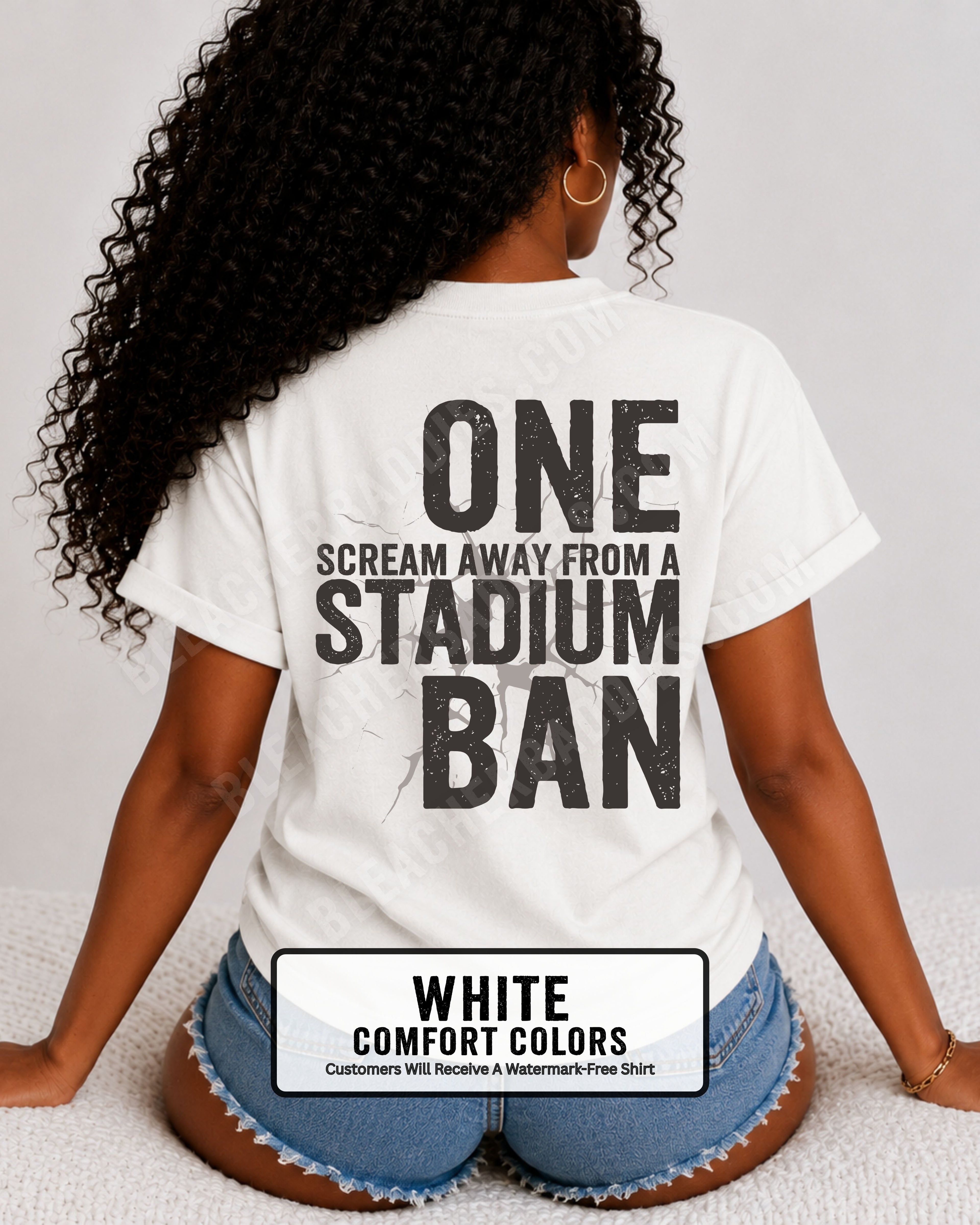 Woman wearing a white comfort colors t-shirt with a large distressed black back graphic that reads “One Scream Away From a Stadium Ban” with a cracked texture effect across the design. Football mom shirt. Loud sports mom shirt.