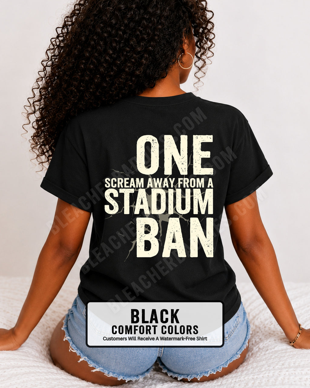 Woman wearing a black comfort colors t-shirt with a large distressed cream back graphic that reads “One Scream Away From a Stadium Ban” with a cracked texture effect across the design. Football mom shirt. Loud sports mom shirt.
