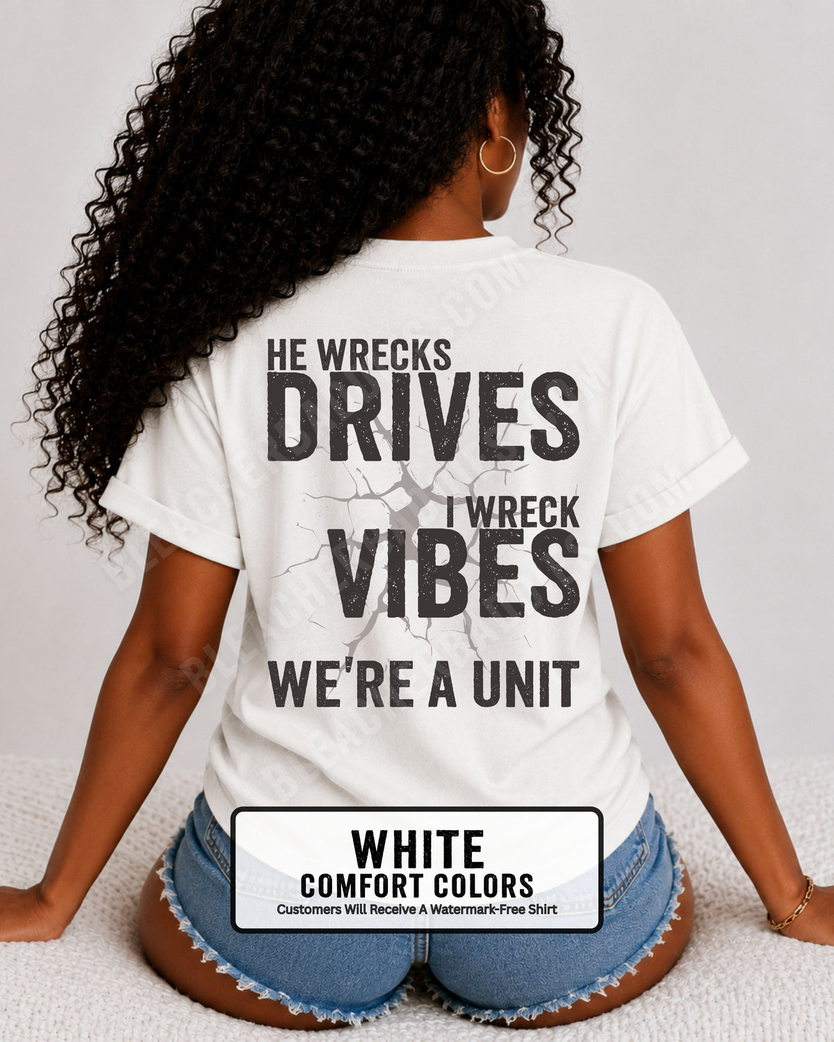 Woman wearing a white Comfort Colors t-shirt shown from the back featuring a large distressed black graphic that reads “He Wrecks Drives I Wreck Vibes We’re a Unit.” Football Mom Shirt