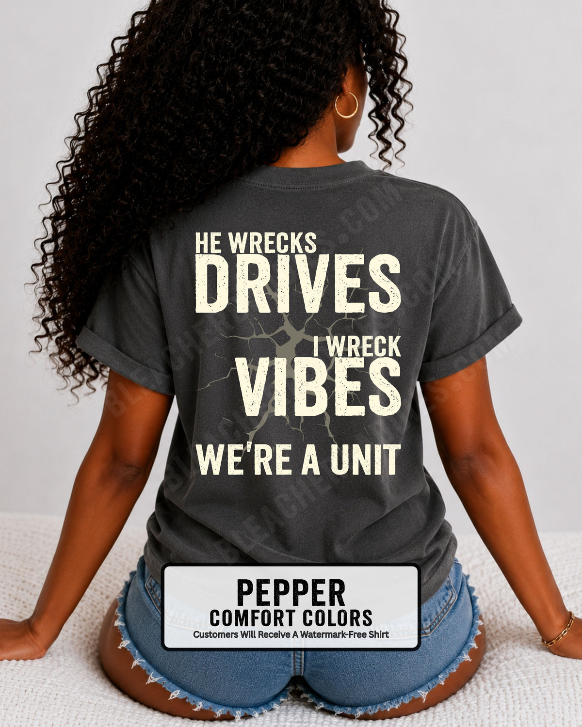 Woman wearing a pepper Comfort Colors t-shirt shown from the back featuring a large distressed black graphic that reads “He Wrecks Drives I Wreck Vibes We’re a Unit.” Football Mom Shirt