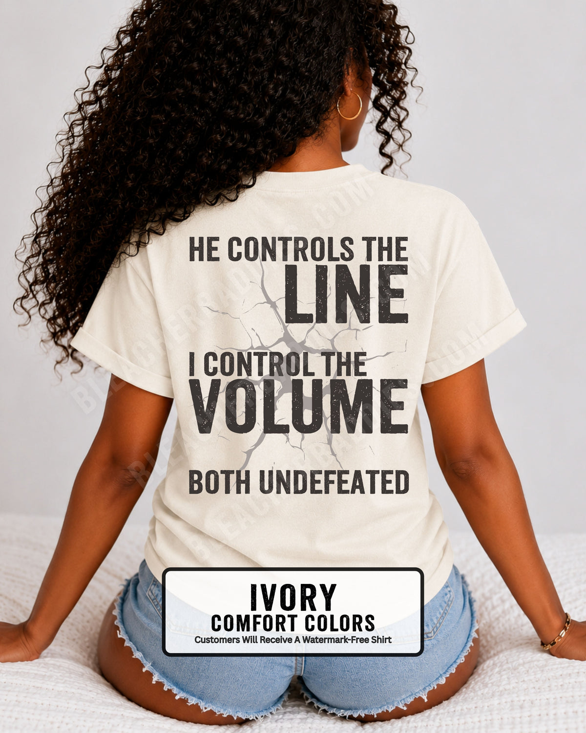 Back view of woman wearing ivory Comfort Colors football mom game day shirt featuring “He Controls the Line I Control the Volume Both Undefeated” bold graphic design. Lineman Mom Shirt.