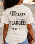 An ivory comfort colors t-shirt worn in stadium with back design that reads “He gets pancakes I get flagged worth it” in distressed black text with cracked graphic. Football mom shirt. Lineman mom shirt. Football Pancakes Shirt.