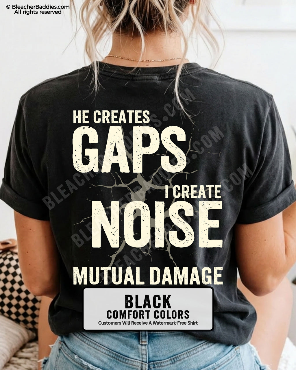 Woman wearing BLACK Comfort Colors football mom game day shirt with back design that reads “He creates gaps I create noise mutual damage” in distressed CREAM text with cracked graphic and chambray color label shown