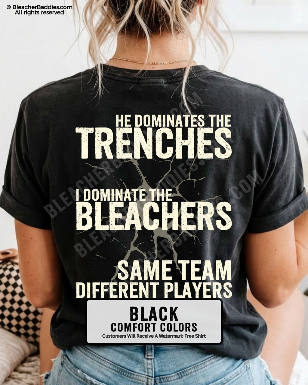 Close-up of woman wearing black comfort colors t-shirt back print with distressed text “He Dominates the Trenches I Dominate the Bleachers Same Team Different Players” and cracked design detail