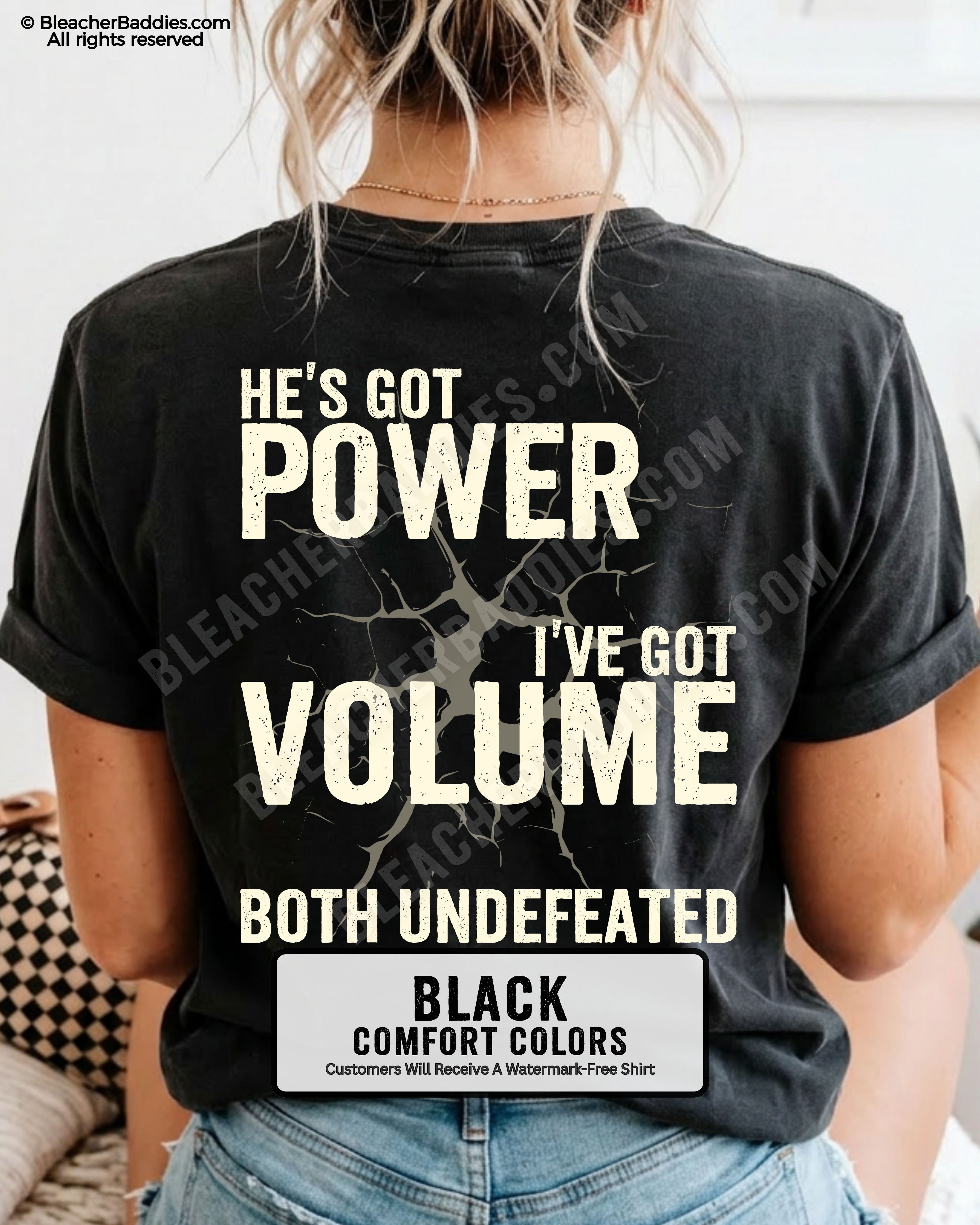 Back view of BLACK Comfort Colors football mom game day shirt reading “He’s Got Power I’ve Got Volume Both Undefeated,” close-up fit on woman wearing denim shorts