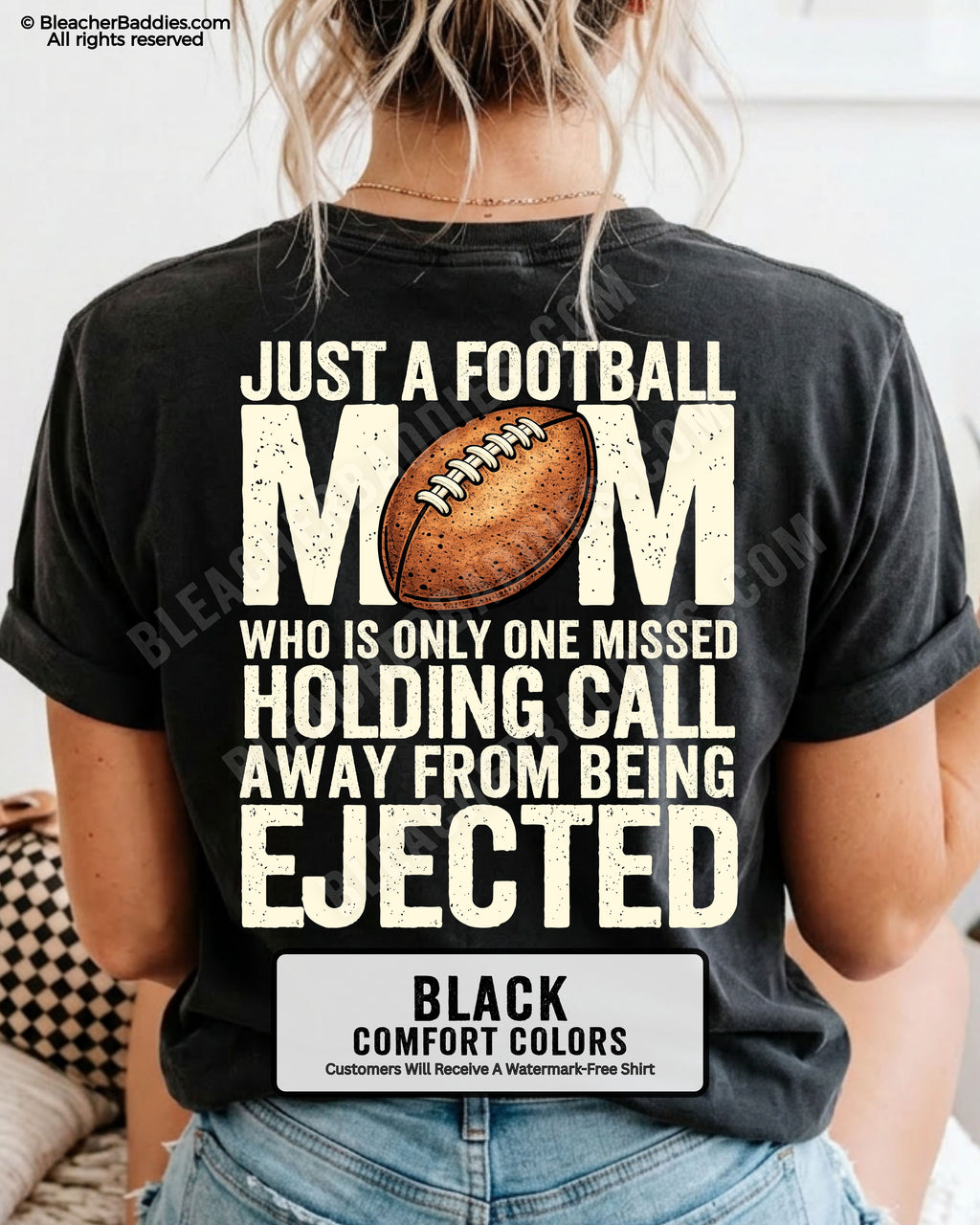Back view of a woman wearing a black Comfort Colors football mom shirt, displaying bold distressed text that reads “Just a football mom who is only one missed holding call away from being ejected,” with a football graphic on the back.
