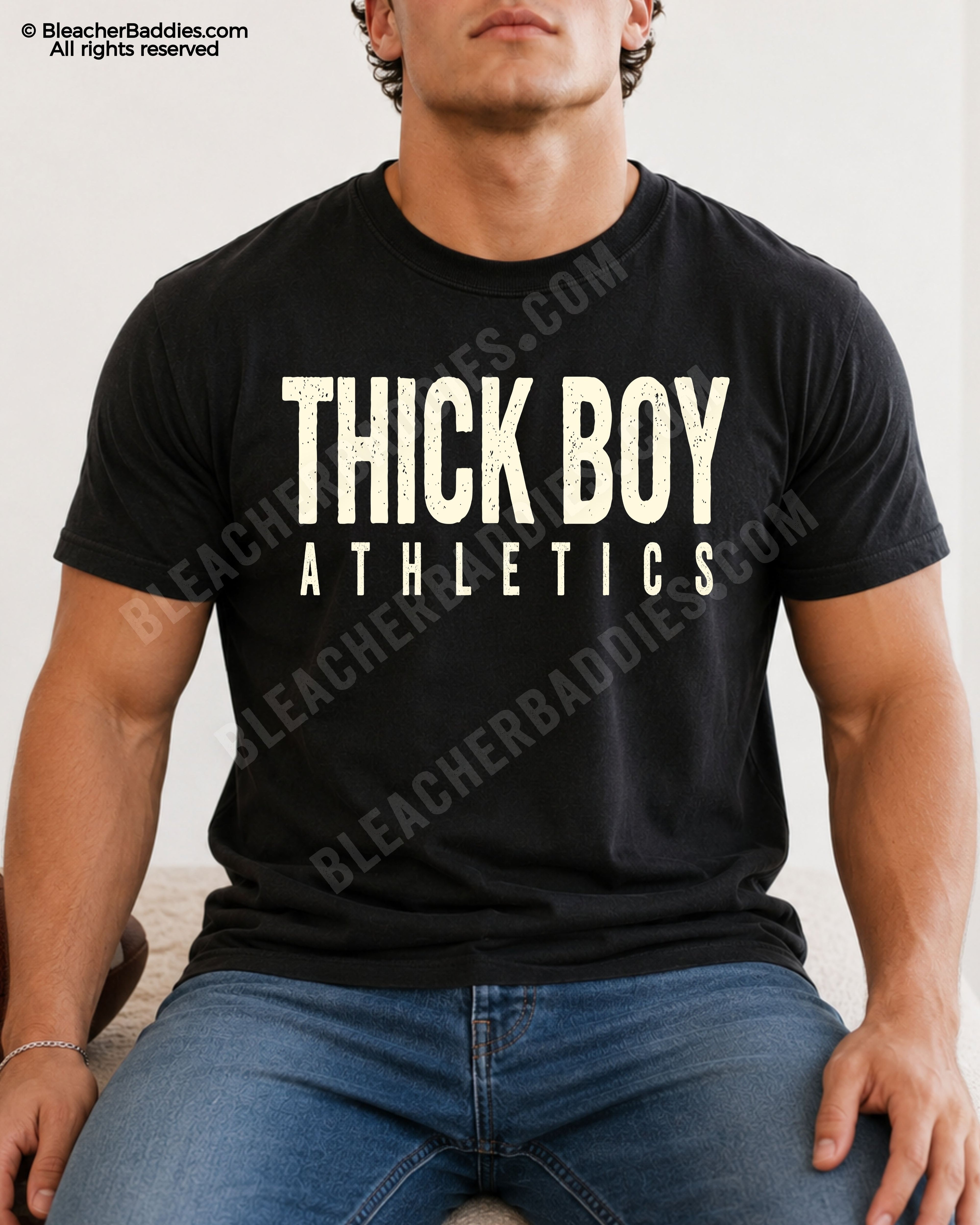Male football player sitting indoors wearing a black Comfort Colors shirt with distressed “Thick Boy Athletics” design and relaxed athletic fit.