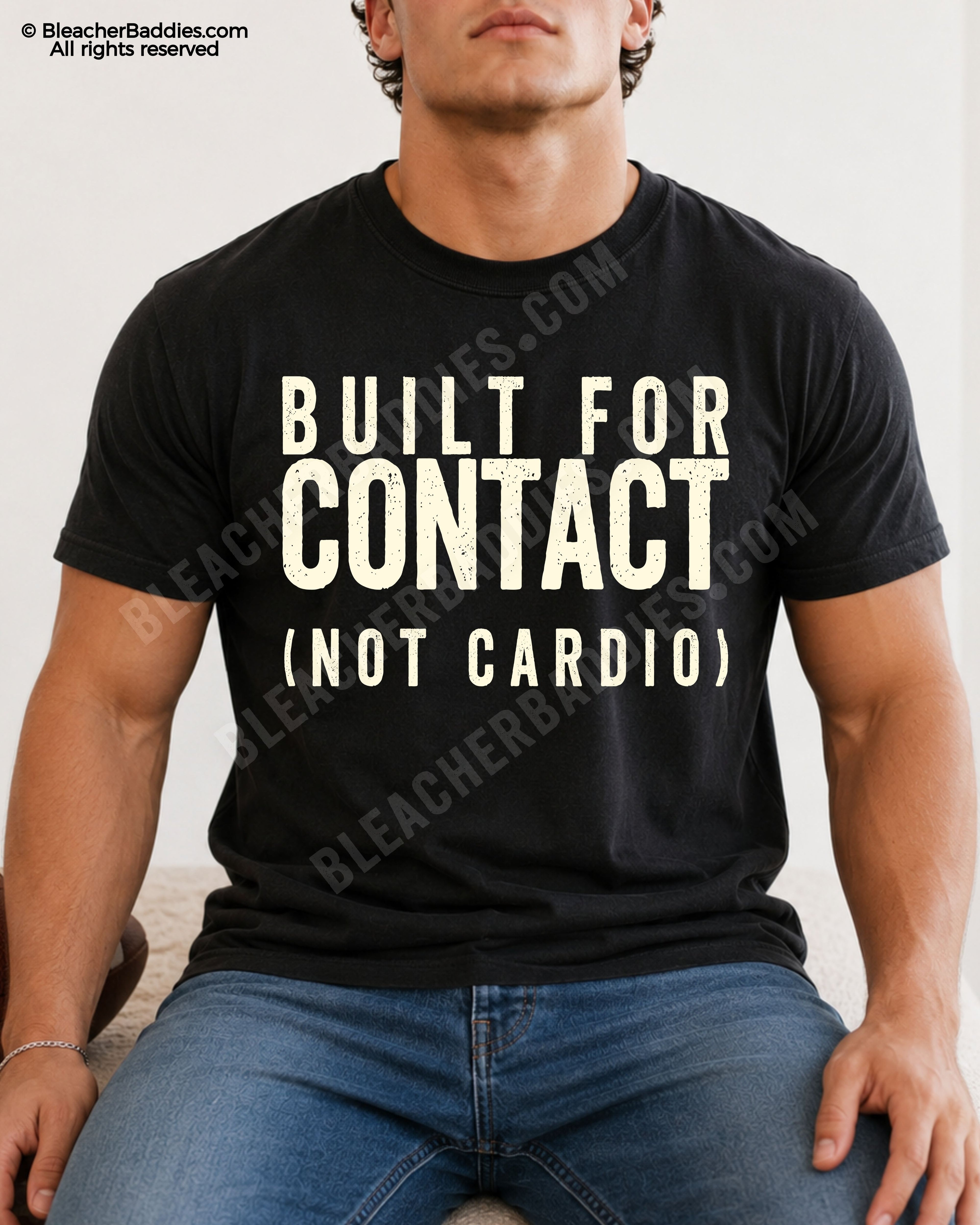 Male football player model wearing a black Comfort Colors “Built For Contact (Not Cardio)” football shirt with bold distressed typography while seated indoors in casual denim jeans.