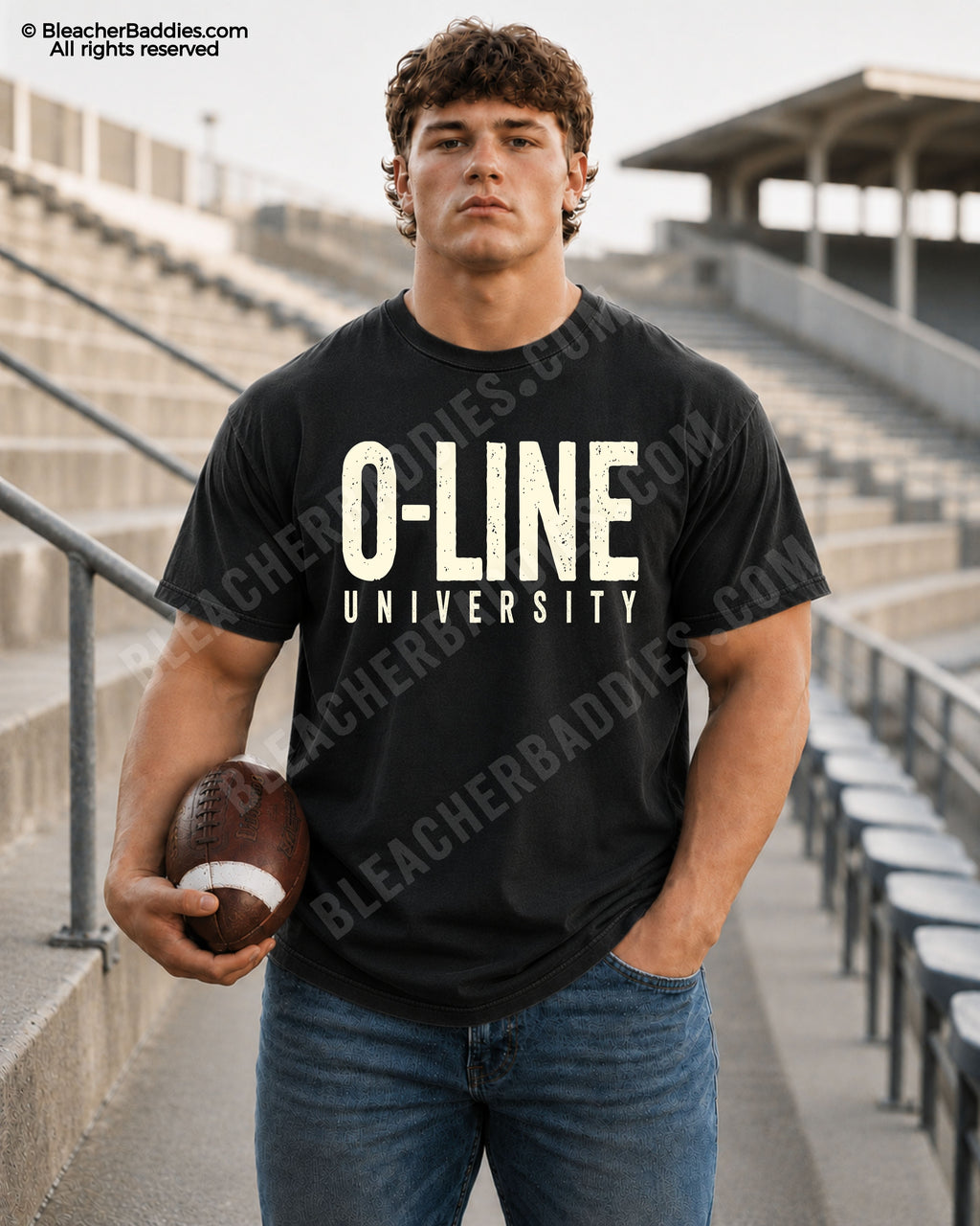 Male football player model wearing a black Comfort Colors “O-Line University” football shirt with bold distressed cream typography while holding a football in stadium bleachers.