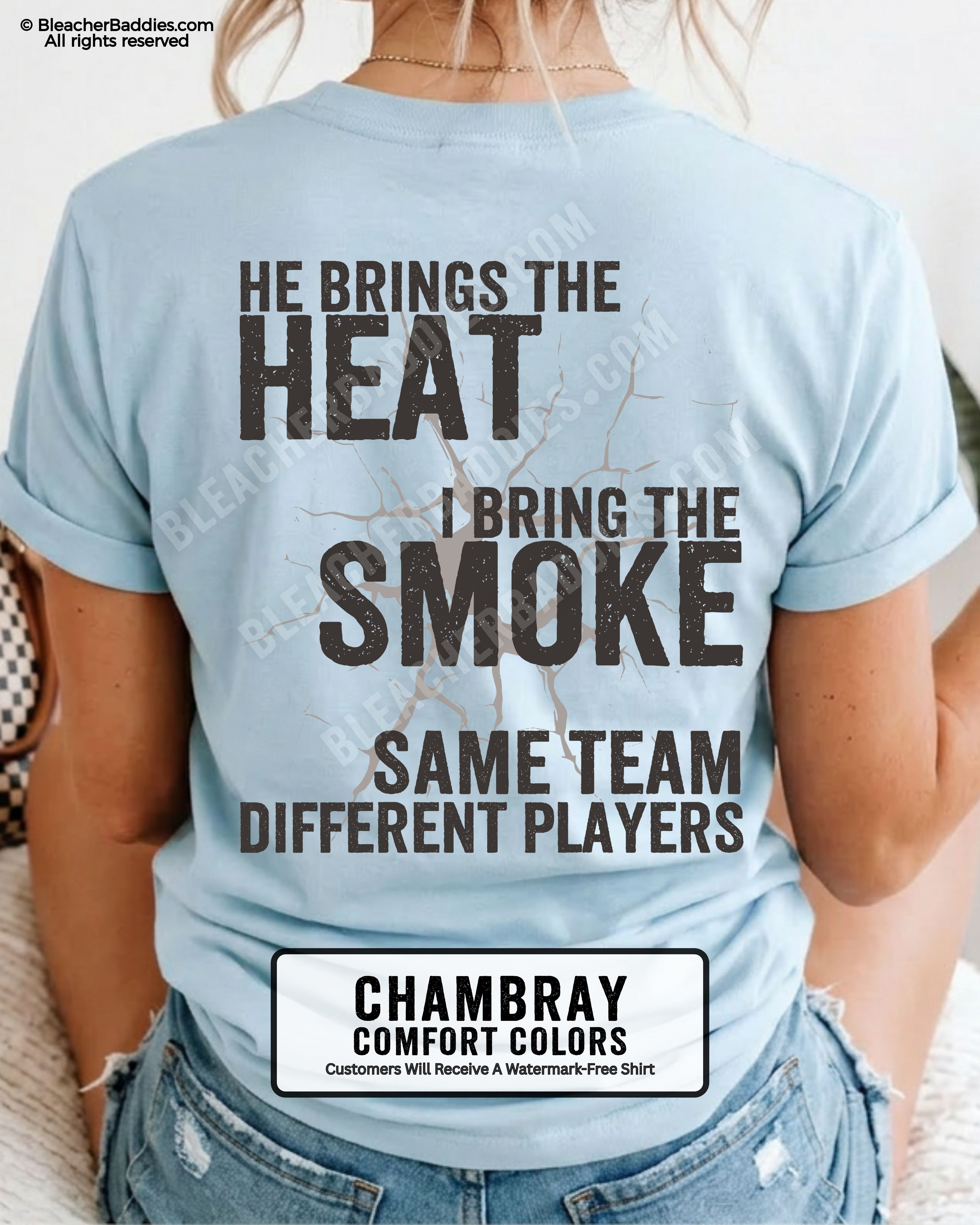 Close-up of CHAMBRAY COMFORT COLORS FOOTBALL MOM t-shirt back print showing distressed text “He Brings the Heat I Bring the Smoke Same Team Different Players” with cracked design detail