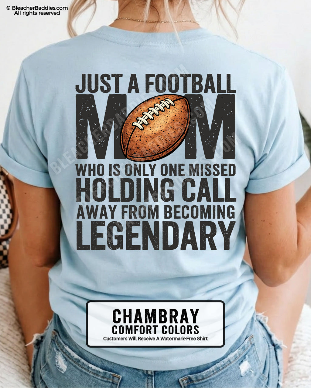 Woman wearing chambray Comfort Colors t-shirt showing back graphic reading “Just a football mom who is only one missed holding call away from becoming legendary” with football design