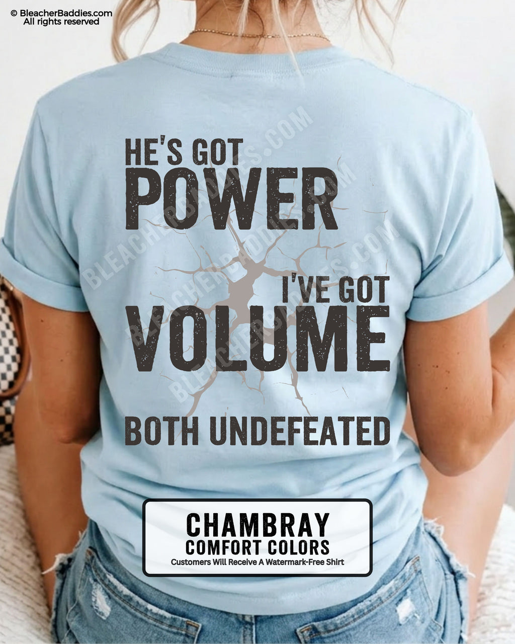 Back view of CHAMBRAY Comfort Colors football mom game day shirt reading “He’s Got Power I’ve Got Volume Both Undefeated,” close-up fit on woman wearing denim shorts