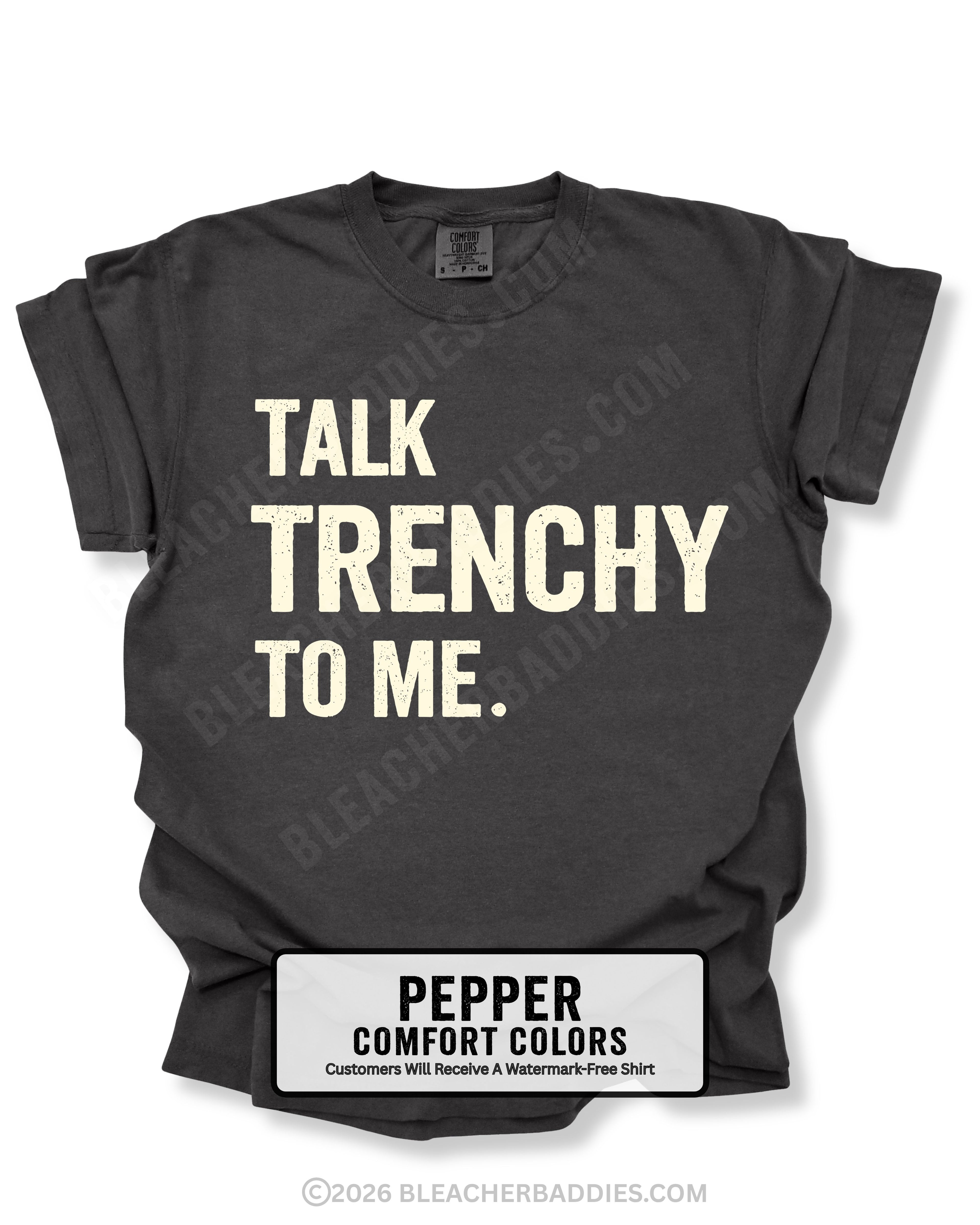 Flat lay of a pepper Comfort Colors t-shirt featuring the distressed ivory text "TALK TRENCHY TO ME." in large block letters. The shirt is displayed on a white background with rolled sleeves, showcasing a bold football offensive line-inspired graphic perfect for linemen, football players, coaches, and trench football fans.