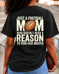 Woman wearing black Comfort Colors t-shirt in stadium bleachers featuring large back print that says “Just a Football Mom Who Doesn’t Need a Reason to Run Her Mouth” with football graphic
