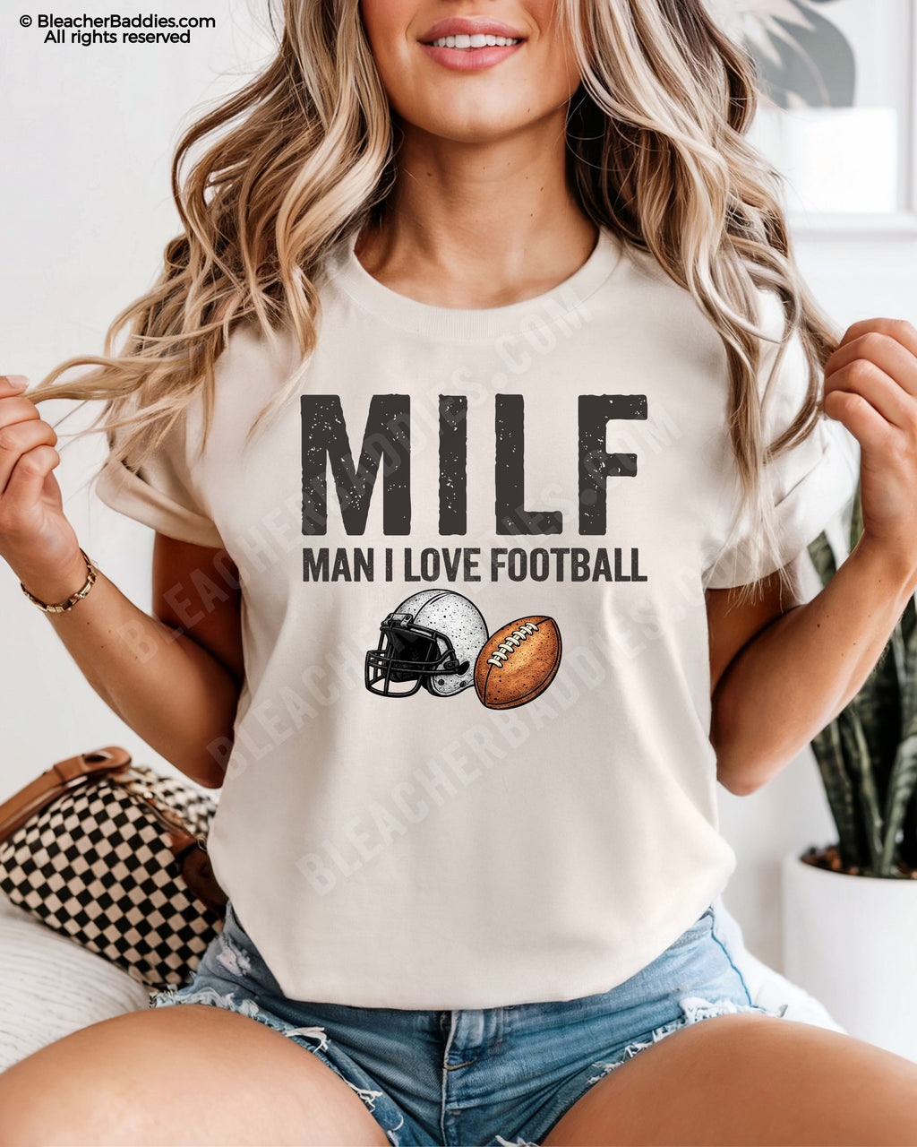 Woman wearing ivory comfort colors t-shirt that says “MILF Man I Love Football” with football helmet and ball graphic