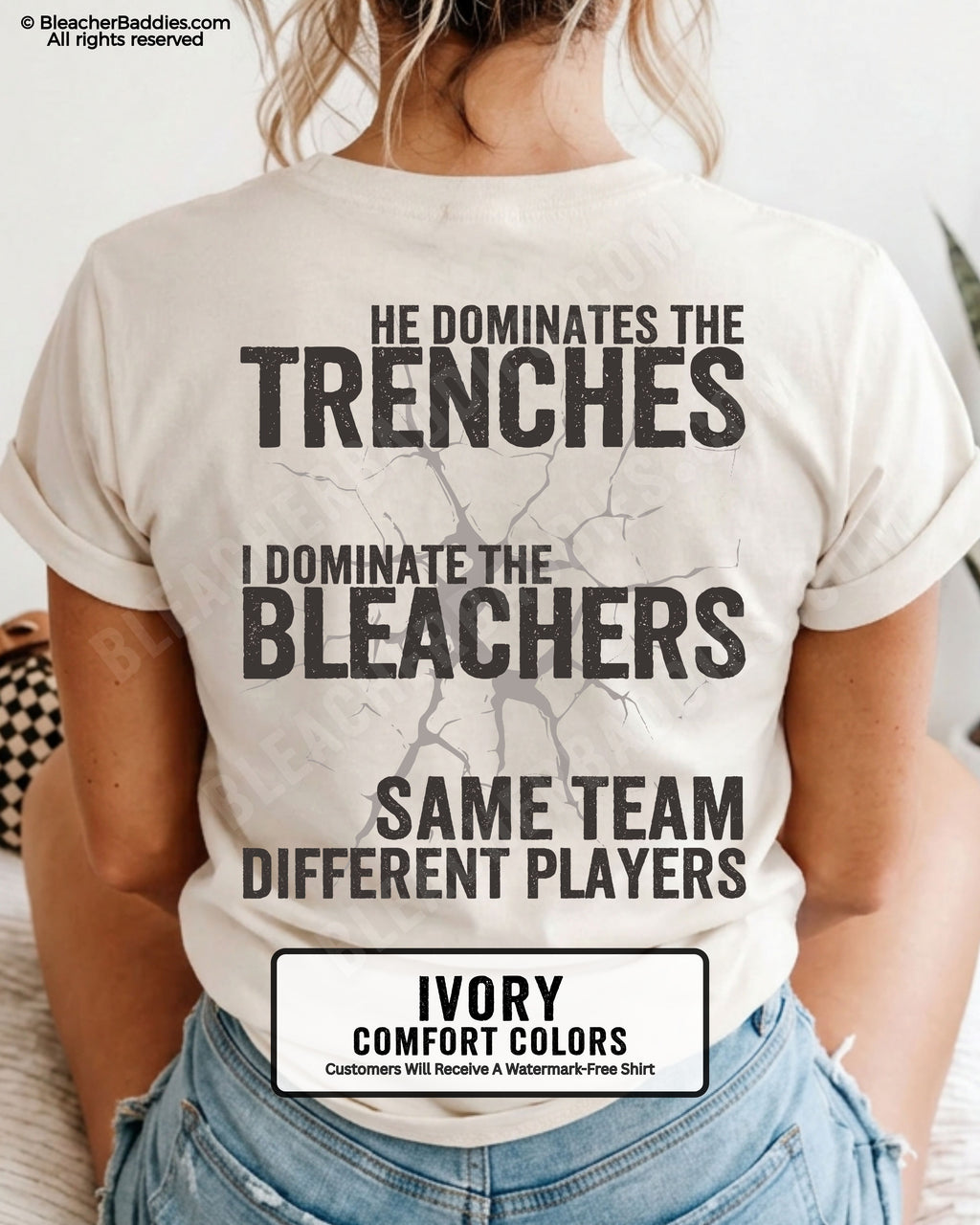 Close-up of woman wearing ivory comfort colors t-shirt back print with distressed text “He Dominates the Trenches I Dominate the Bleachers Same Team Different Players” and cracked design detail