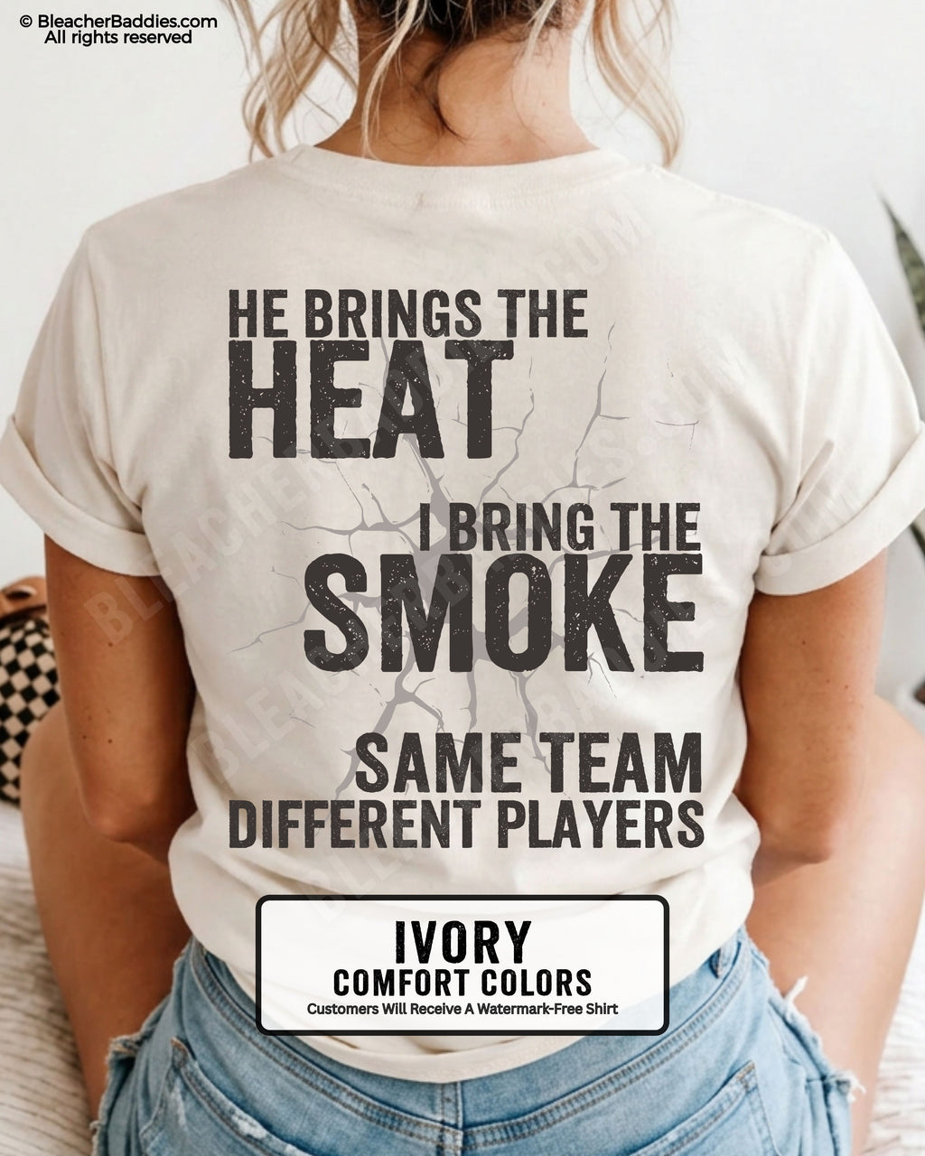 Close-up of IVORY COMFORT COLORS FOOTBALL MOM t-shirt back print showing distressed text “He Brings the Heat I Bring the Smoke Same Team Different Players” with cracked design detail