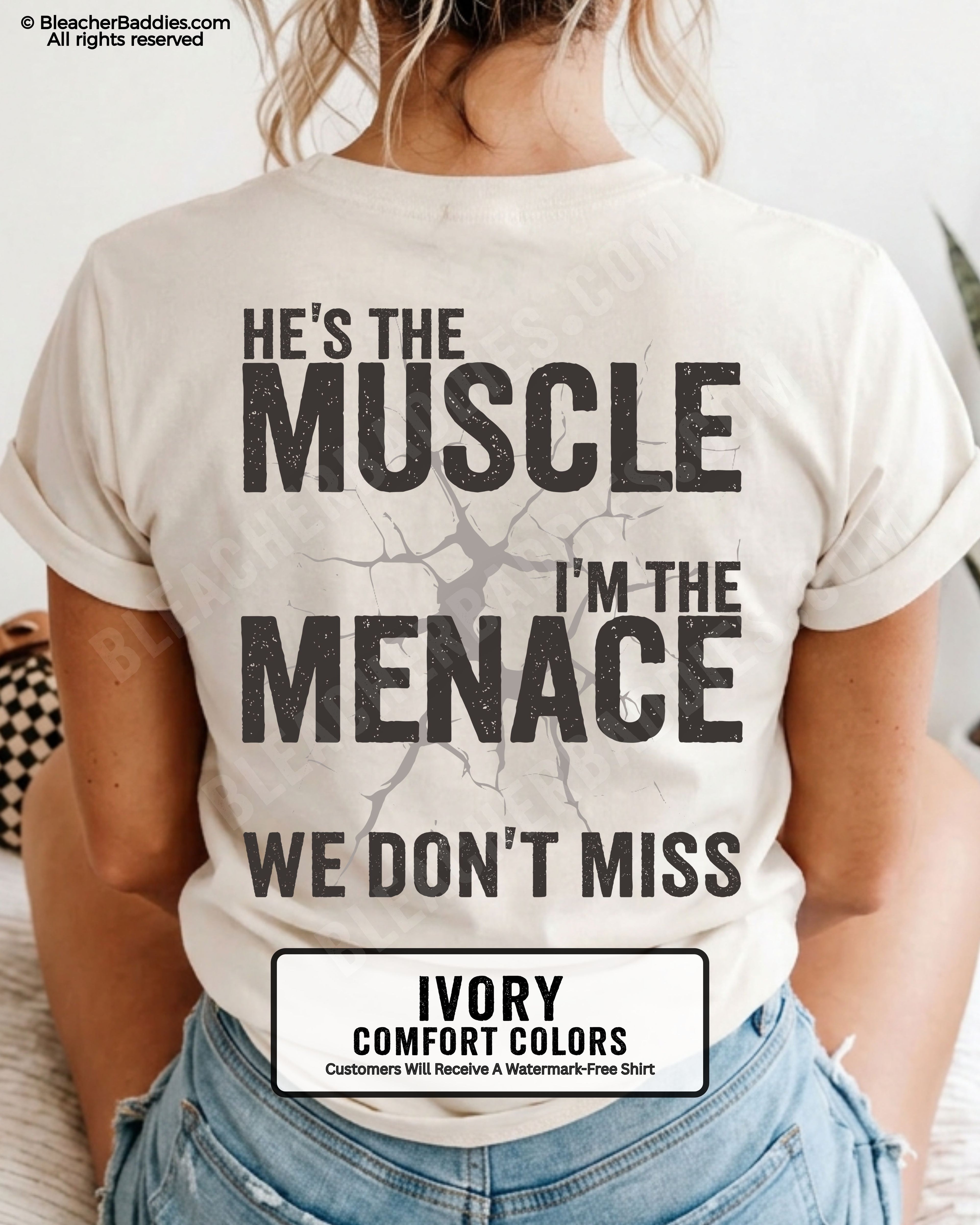 Woman wearing IVORY Comfort Colors football mom game day shirt with back design that reads “He’s the muscle I’m the menace we don’t miss” in distressed black text with cracked graphic and chambray color label shown