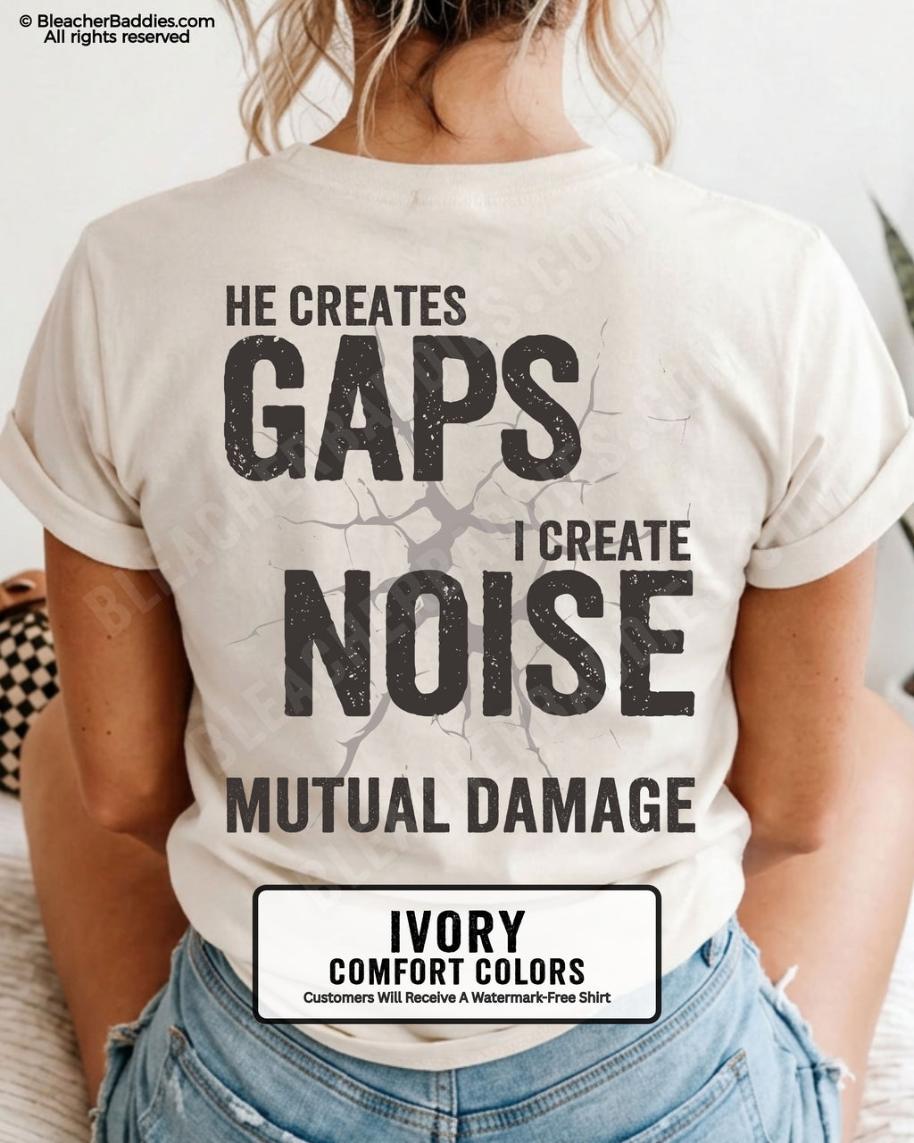 Woman wearing IVORY Comfort Colors football mom game day shirt with back design that reads “He creates gaps I create noise mutual damage” in distressed black text with cracked graphic and chambray color label shown