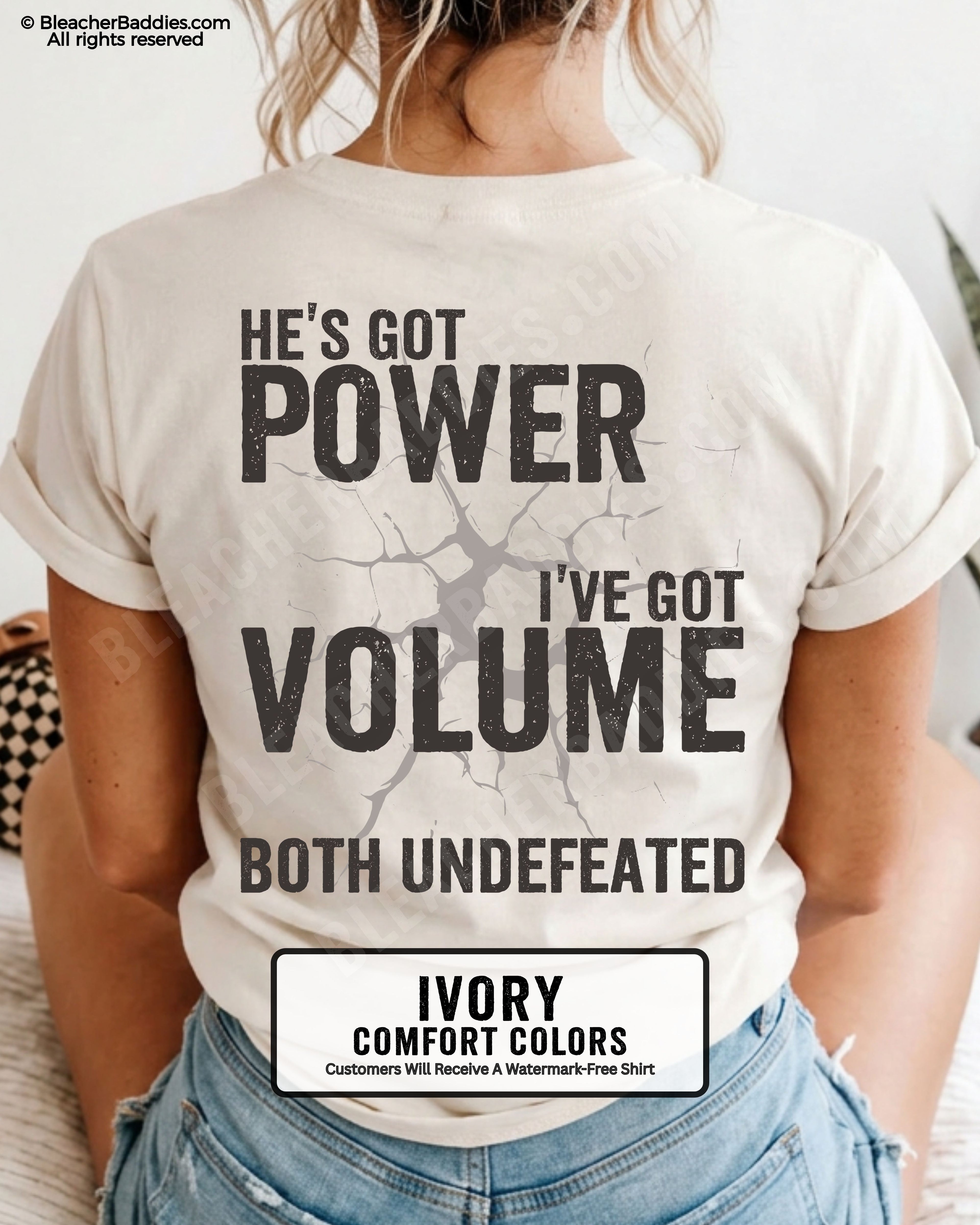 Back view of ivory Comfort Colors football mom game day shirt reading “He’s Got Power I’ve Got Volume Both Undefeated,” close-up fit on woman wearing denim shorts