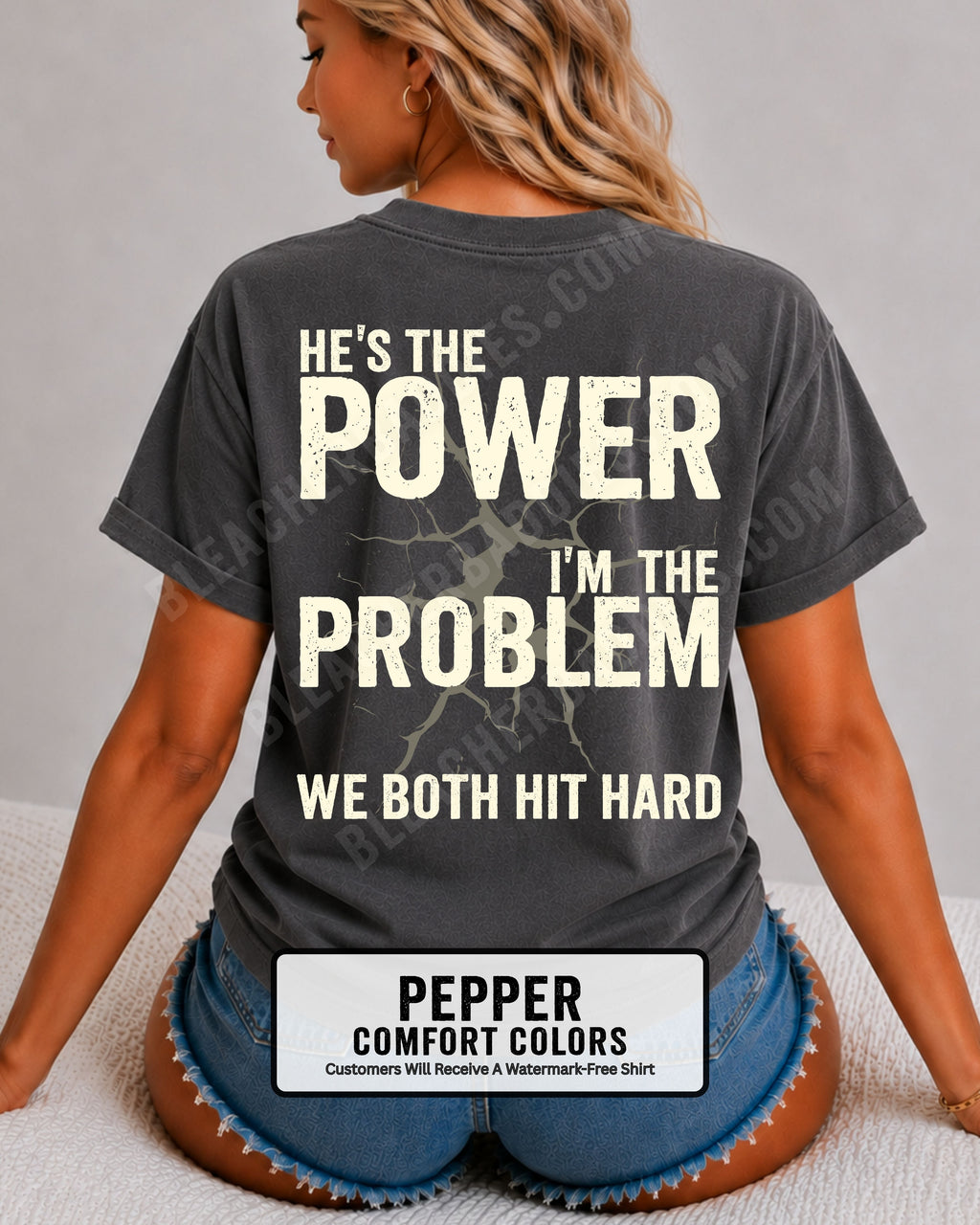 Back view of pepper Comfort Colors football mom game day shirt reading “He’s the Power I’m the Problem We Both Hit Hard,” close-up fit on woman wearing denim shorts