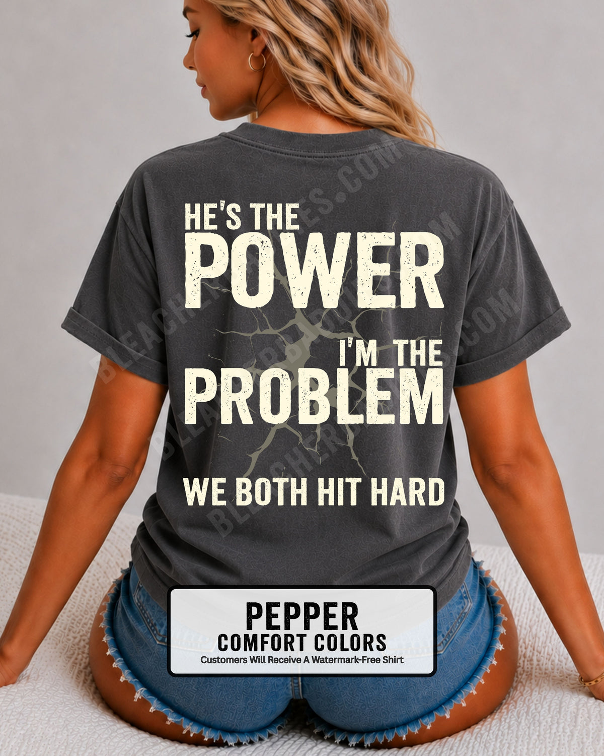 Back view of pepper Comfort Colors football mom game day shirt reading “He’s the Power I’m the Problem We Both Hit Hard,” close-up fit on woman wearing denim shorts