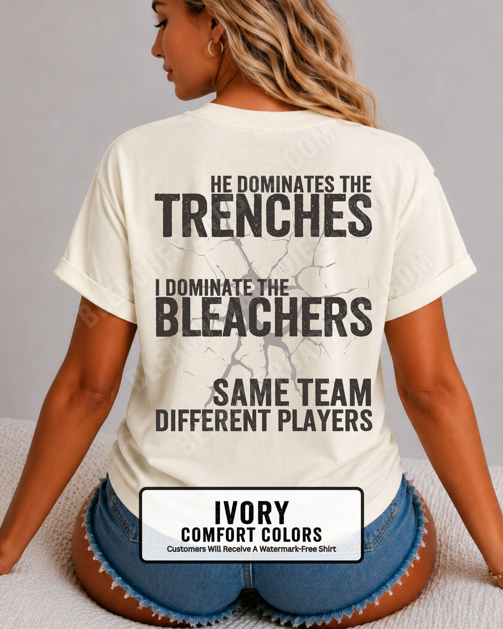 Close-up of woman wearing ivory comfort colors t-shirt back print with distressed text “He Dominates the Trenches I Dominate the Bleachers Same Team Different Players” and cracked design detail