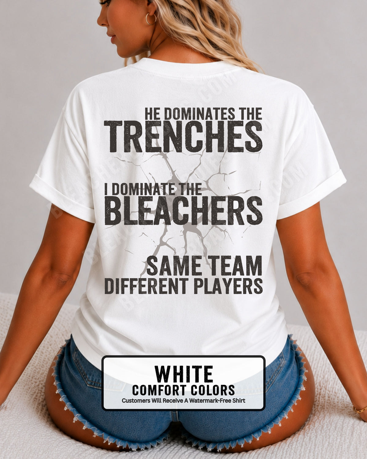 Close-up of woman wearing white comfort colors t-shirt back print with distressed text “He Dominates the Trenches I Dominate the Bleachers Same Team Different Players” and cracked design detail