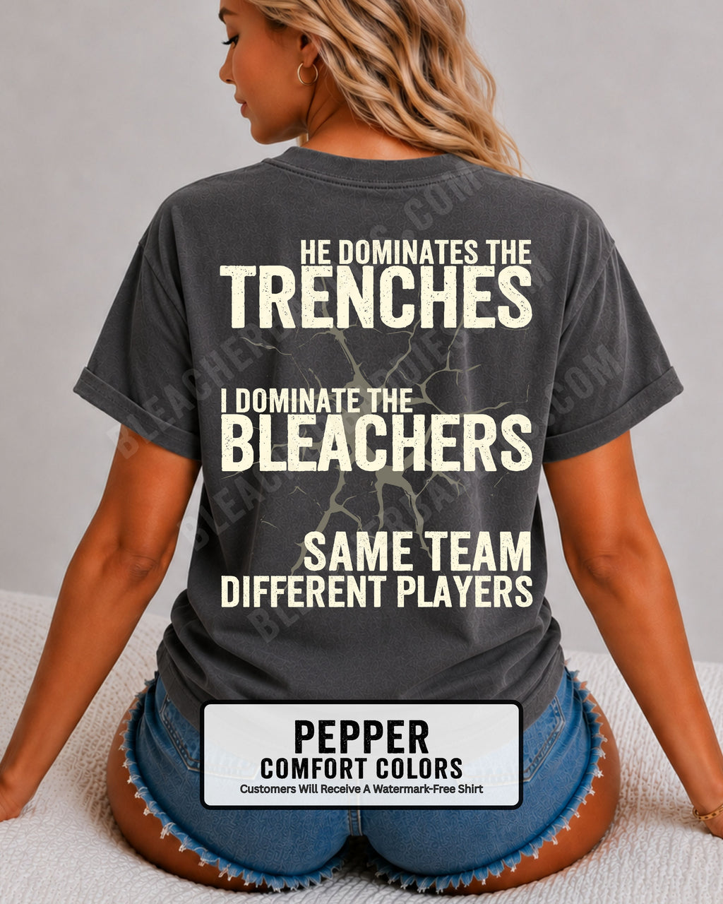 Close-up of woman wearing pepper comfort colors t-shirt back print with distressed text “He Dominates the Trenches I Dominate the Bleachers Same Team Different Players” and cracked design detail