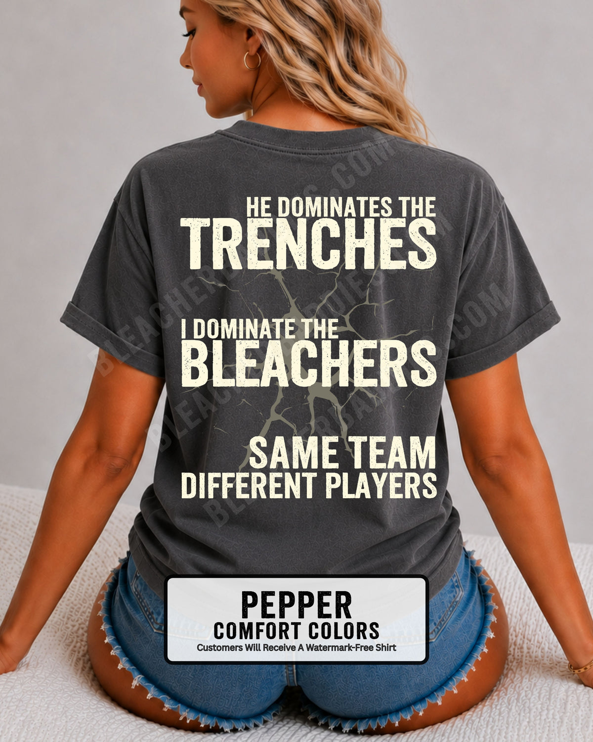 Close-up of woman wearing pepper comfort colors t-shirt back print with distressed text “He Dominates the Trenches I Dominate the Bleachers Same Team Different Players” and cracked design detail