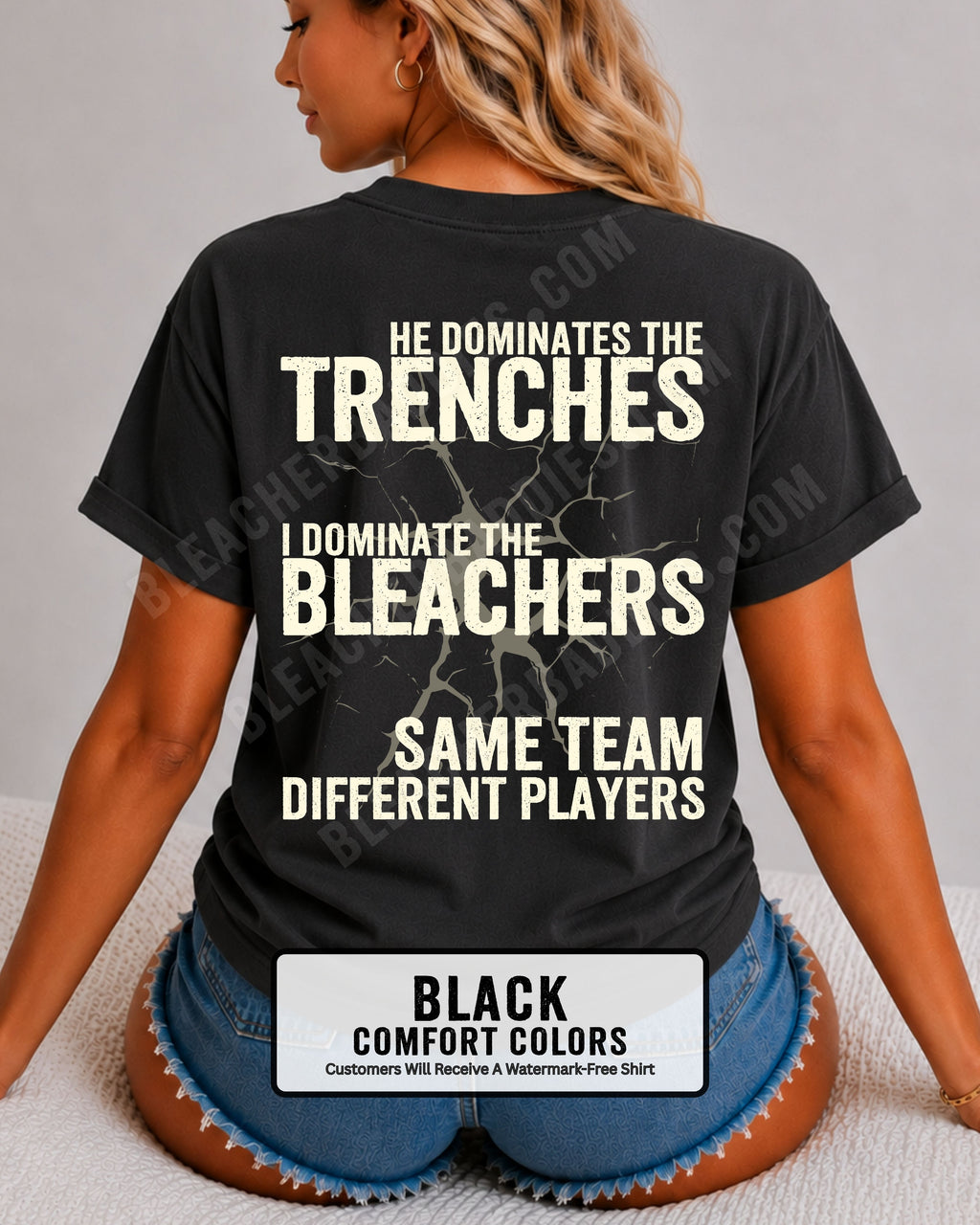 Close-up of woman wearing black comfort colors t-shirt back print with distressed text “He Dominates the Trenches I Dominate the Bleachers Same Team Different Players” and cracked design detail
