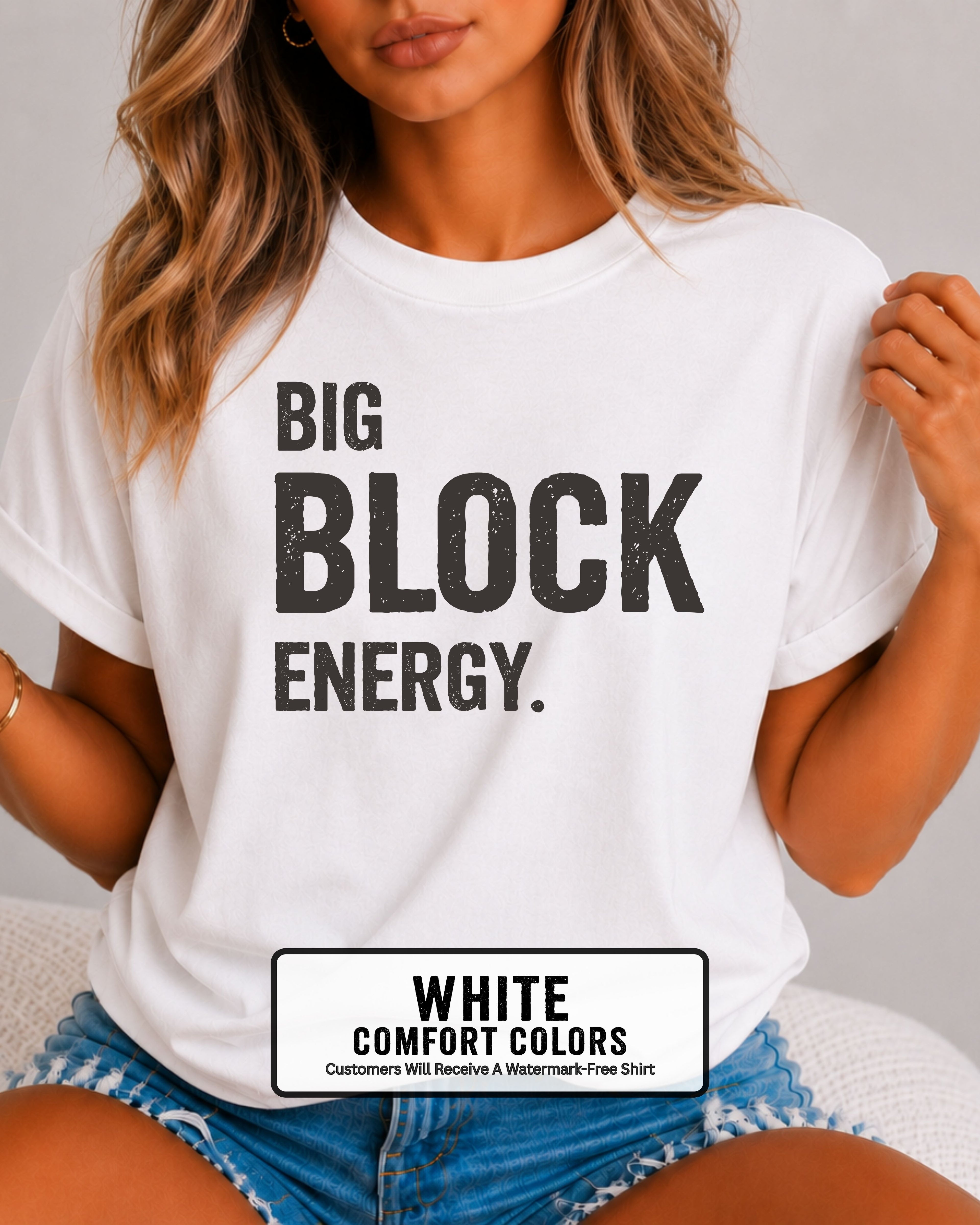 woman wearing a white Comfort Colors t-shirt featuring the phrase "Big Block Energy" in distressed dark lettering. She is seated in light blue patterned shorts, making this the perfect football game day shirt for football moms, offensive line moms, lineman girlfriends, wives, and fans who love the big guys in the trenches.