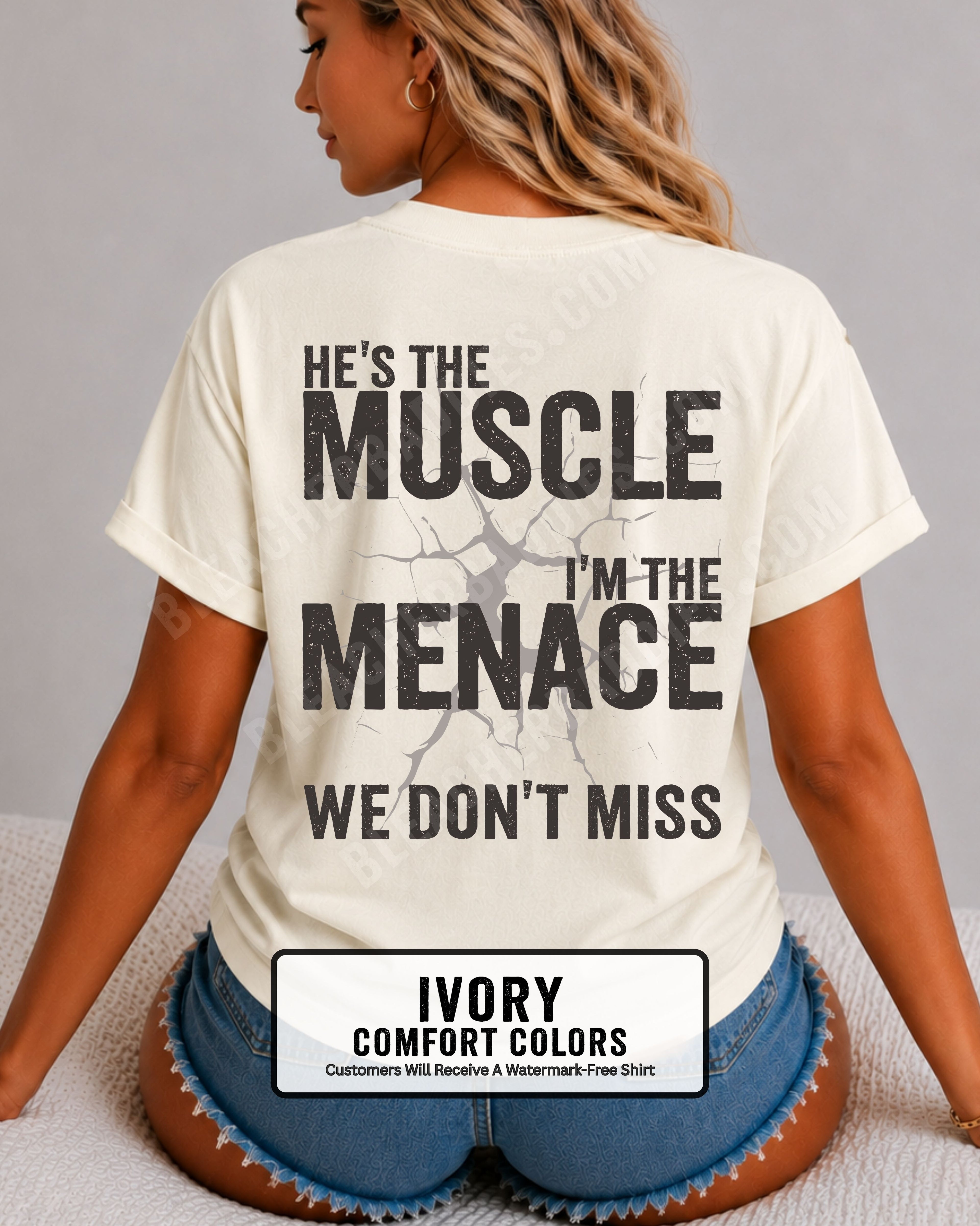 Woman wearing IVORY Comfort Colors football mom game day shirt with back design that reads “He’s the muscle I’m the menace we don’t miss” in distressed black text with cracked graphic.  Football mom shirt.  Lineman mom shirt.