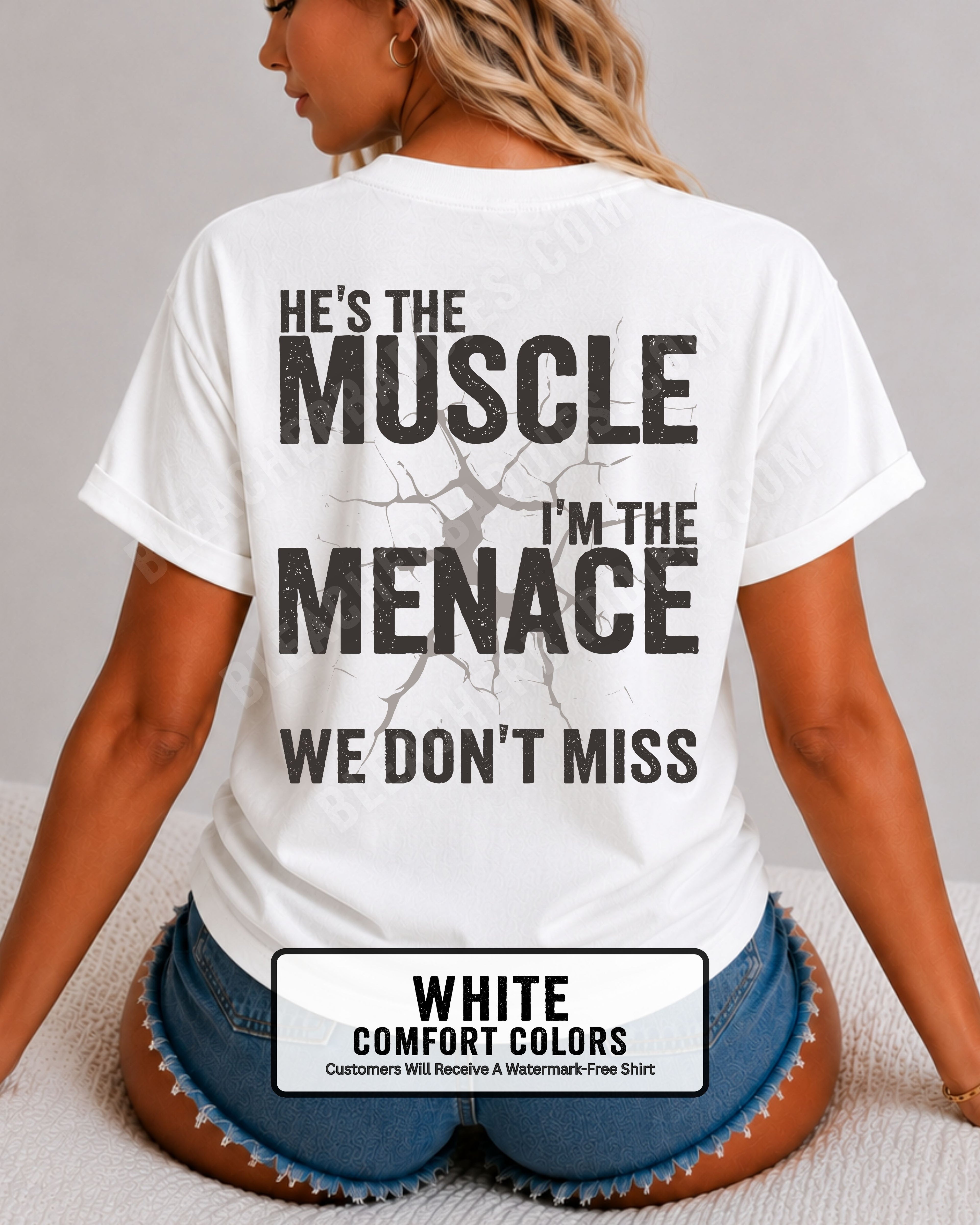 Woman wearing white Comfort Colors football mom game day shirt with back design that reads “He’s the muscle I’m the menace we don’t miss” in distressed black text with cracked graphic.  Football mom shirt.  Lineman mom shirt.