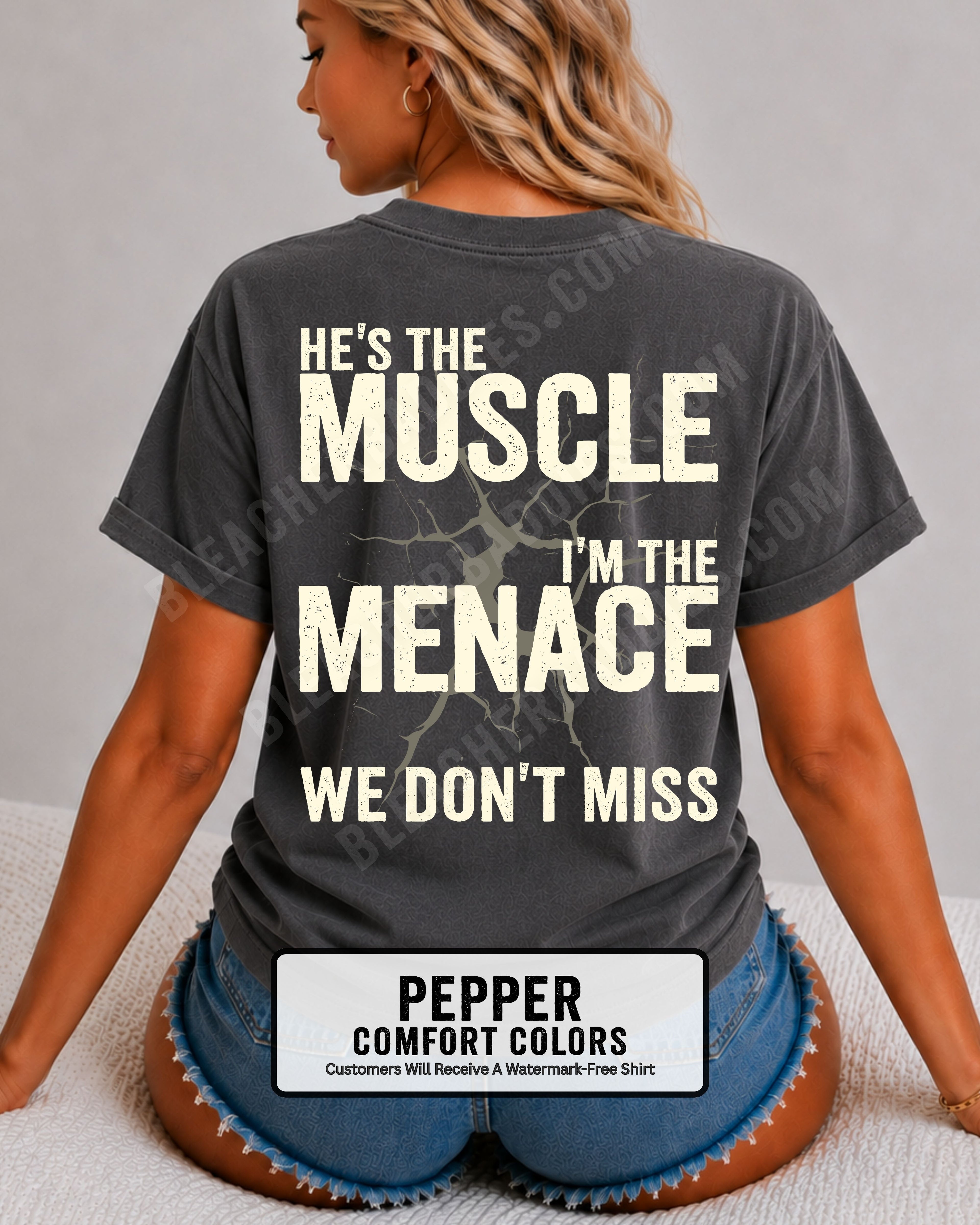 Woman wearing IVORY Comfort Colors football mom game day shirt with back design that reads “He’s the muscle I’m the menace we don’t miss” in distressed cream text with cracked graphic.  Football mom shirt.  Lineman mom shirt.