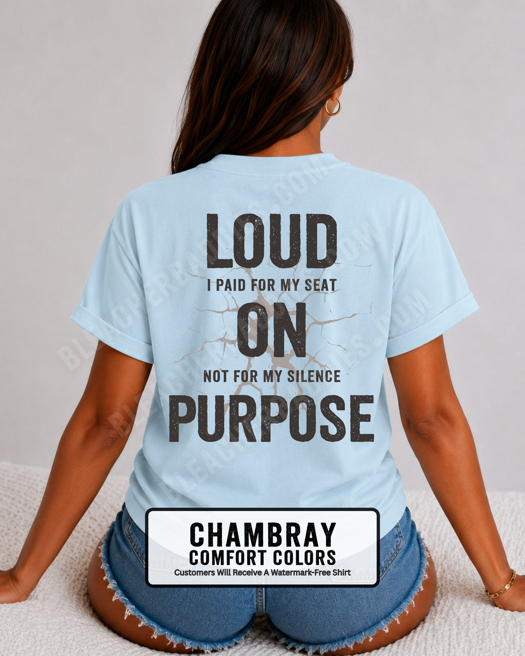 Woman wearing a chambray blue Comfort Colors t-shirt shown from the back featuring a large distressed black graphic that reads “Loud I Paid for My Seat On Purpose Not For My Silence” with a cracked texture effect.