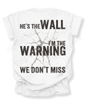 White football mom game day shirt shown from the back featuring a large distressed black graphic that reads “He’s the Wall I’m the Warning We Don’t Miss.” Offensive Lineman Mom Shirt. Defensive Lineman Mom Shirt. Football Mom Shirt.