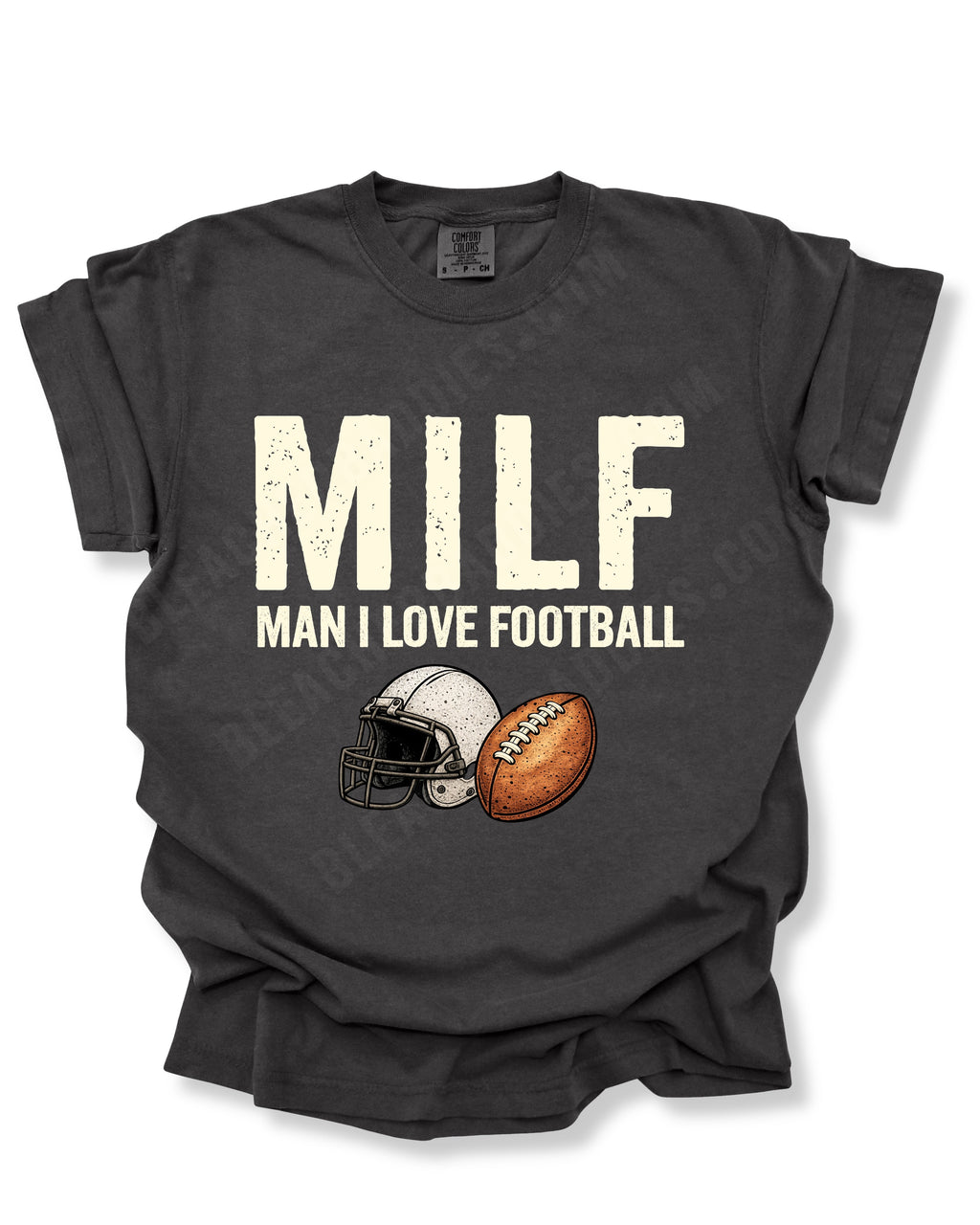 Flat lay of a pepper Comfort Colors t-shirt featuring the distressed ivory text "MILF" with the phrase "MAN I LOVE FOOTBALL" underneath, along with a vintage-style white football helmet and brown football graphic. The shirt is displayed on a white background with rolled sleeves, creating a bold and humorous football fan design perfect for football moms, tailgates, and game day.