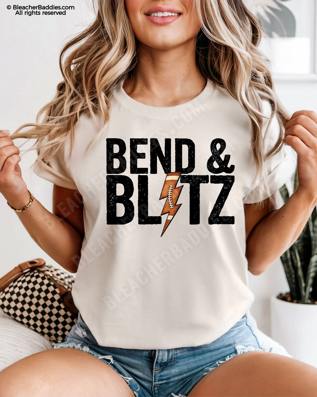 Front view of an ivory Comfort Colors t-shirt featuring the phrase "Bend & Blitz" in bold distressed lettering with a textured football lightning bolt graphic replacing the letter "I" for a trendy football game day design.