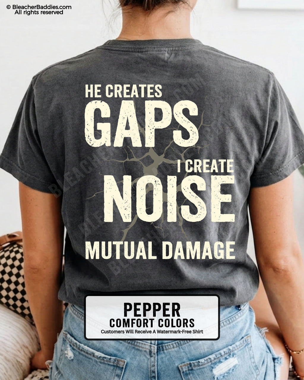Woman wearing PEPPER Comfort Colors football mom game day shirt with back design that reads “He creates gaps I create noise mutual damage” in distressed CREAM text with cracked graphic and chambray color label shown