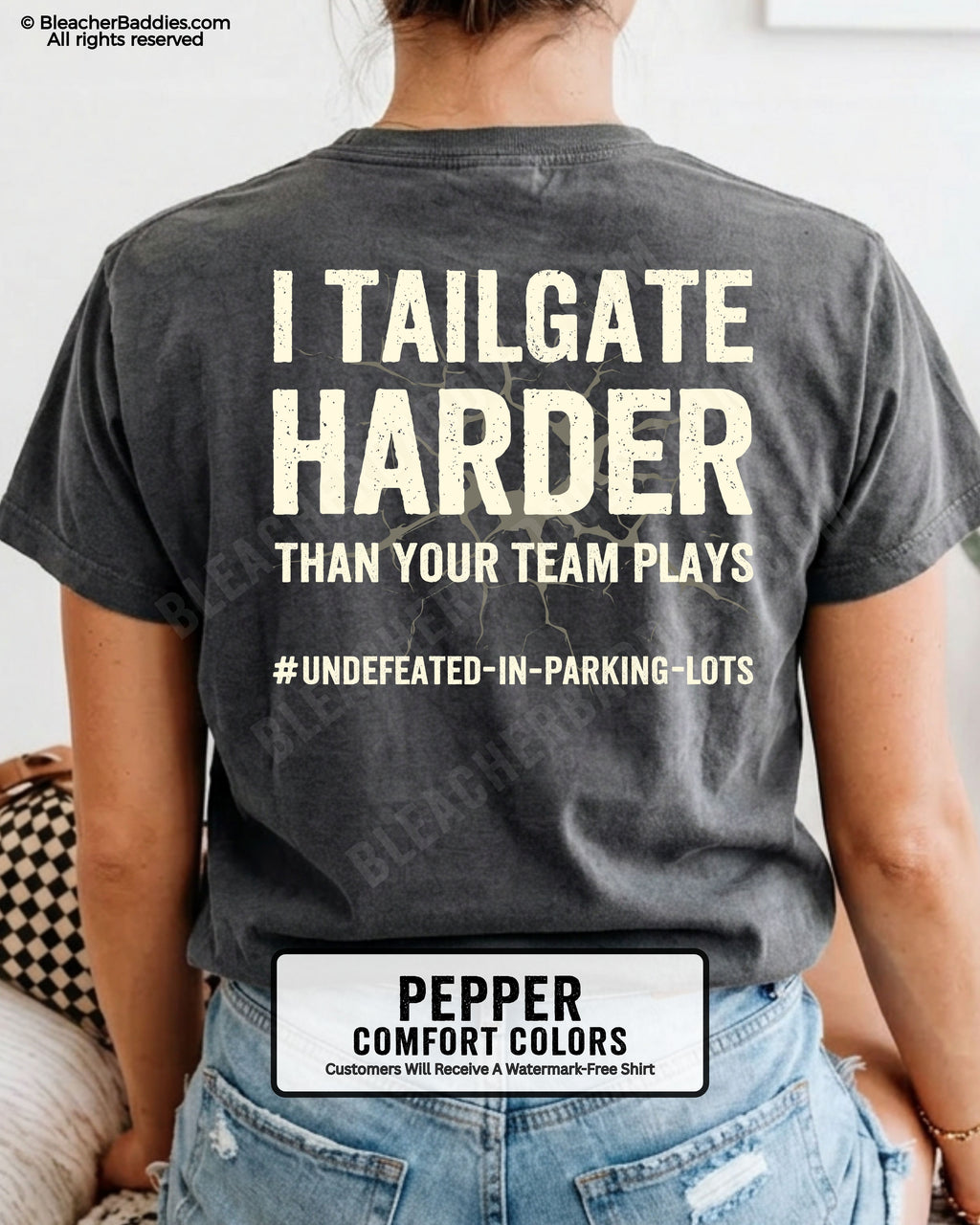 Woman wearing PEPPER Comfort Colors football mom game day shirt with back design that reads “I tailgate harder than your team plays #undefeated-in-parking-lots” in distressed CREAM text with cracked graphic and chambray color label shown