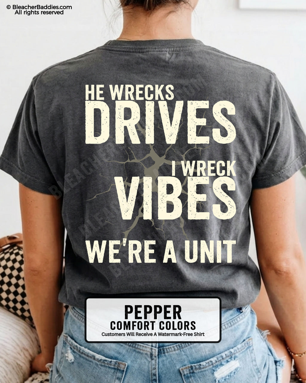 Woman wearing a pepper Comfort Colors t-shirt shown from the back featuring a large distressed cream graphic that reads “He Wrecks Drives I Wreck Vibes We’re a Unit.”