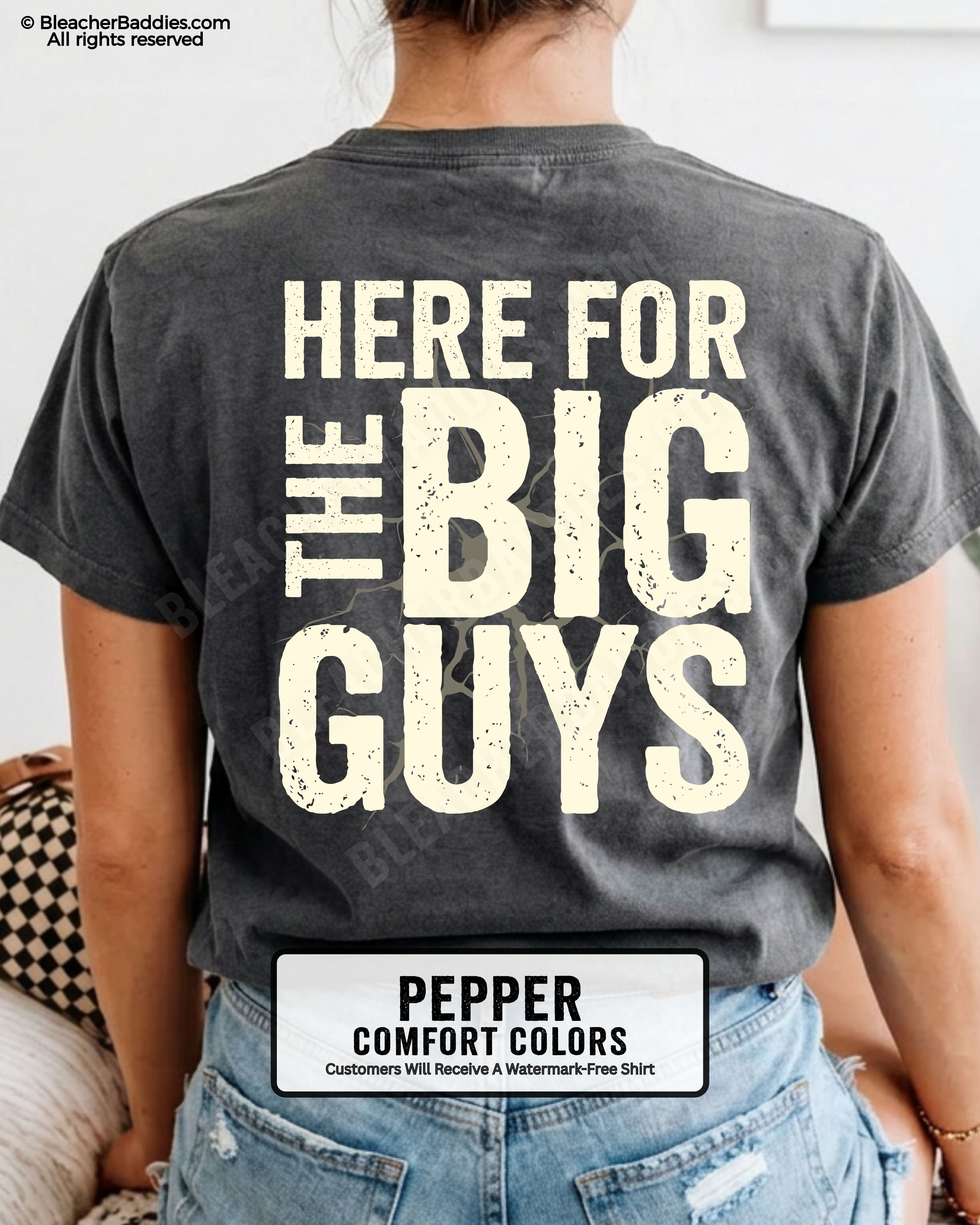 Close-up of football mom wearing a pepper comfort colors game day shirt showing distressed cream text “Here for the big guys” with cracked effect graphic behind lettering