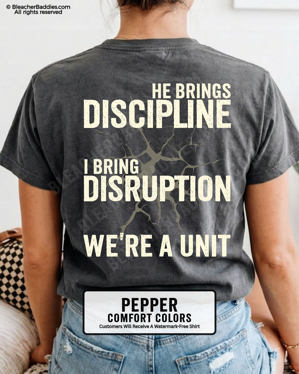 Back view of PEPPER Comfort Colors football mom game day shirt featuring “He Brings Discipline I Bring Disruption We’re a Unit” design worn by woman indoors with denim shorts