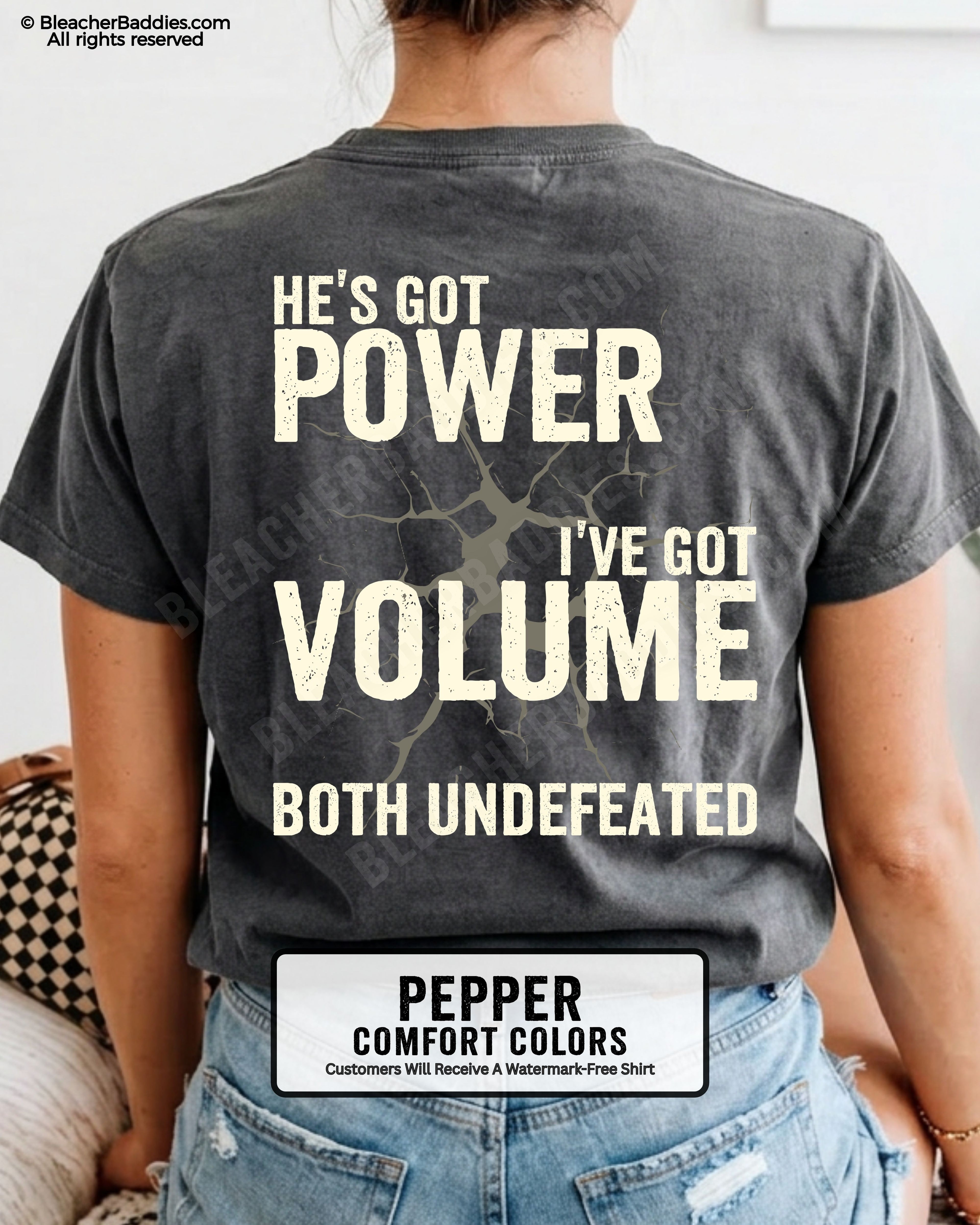 Back view of PEPPER Comfort Colors football mom game day shirt reading “He’s Got Power I’ve Got Volume Both Undefeated,” close-up fit on woman wearing denim shorts