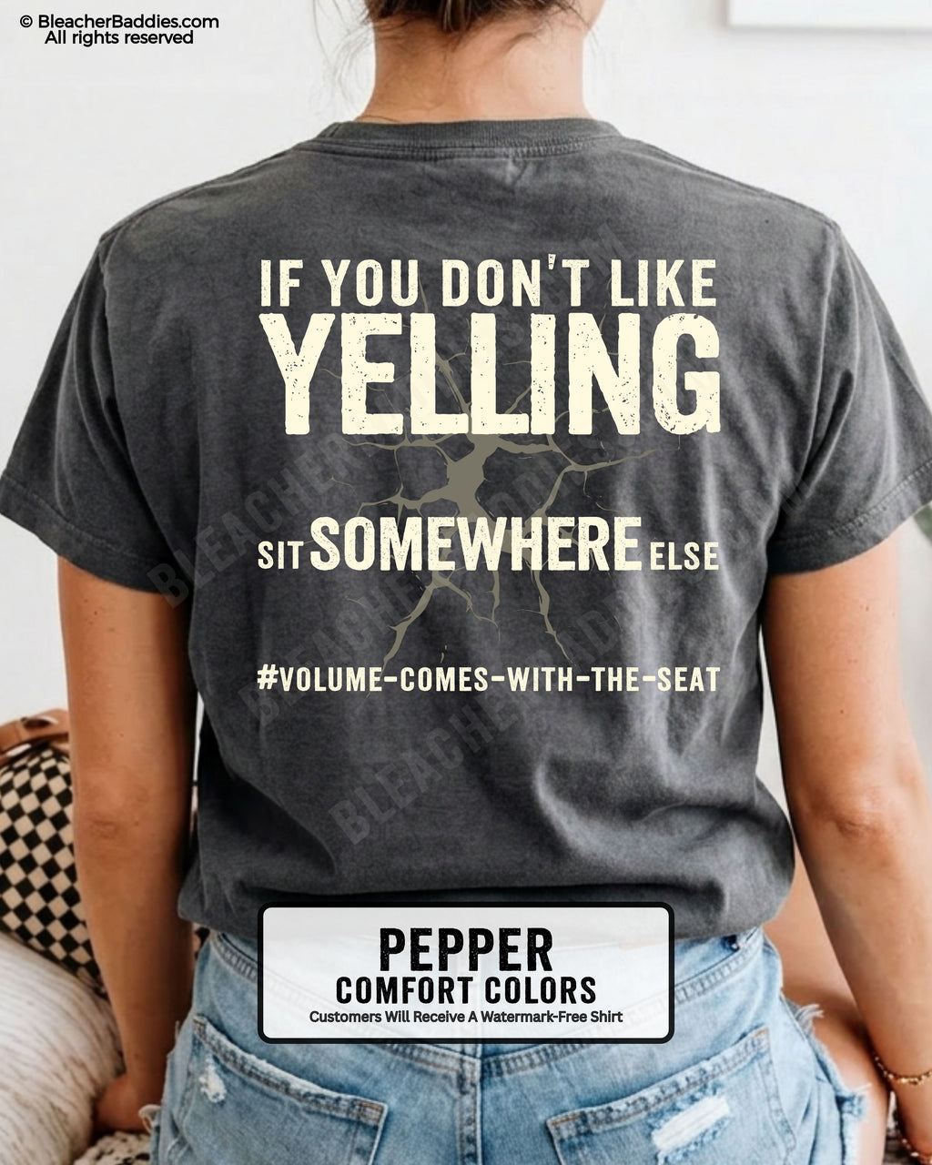 Woman wearing a pepper Comfort Colors t-shirt shown from the back featuring a large distressed cream graphic that reads “If You Don’t Like Yelling Sit Somewhere Else #Volume Comes With the Seat.”
