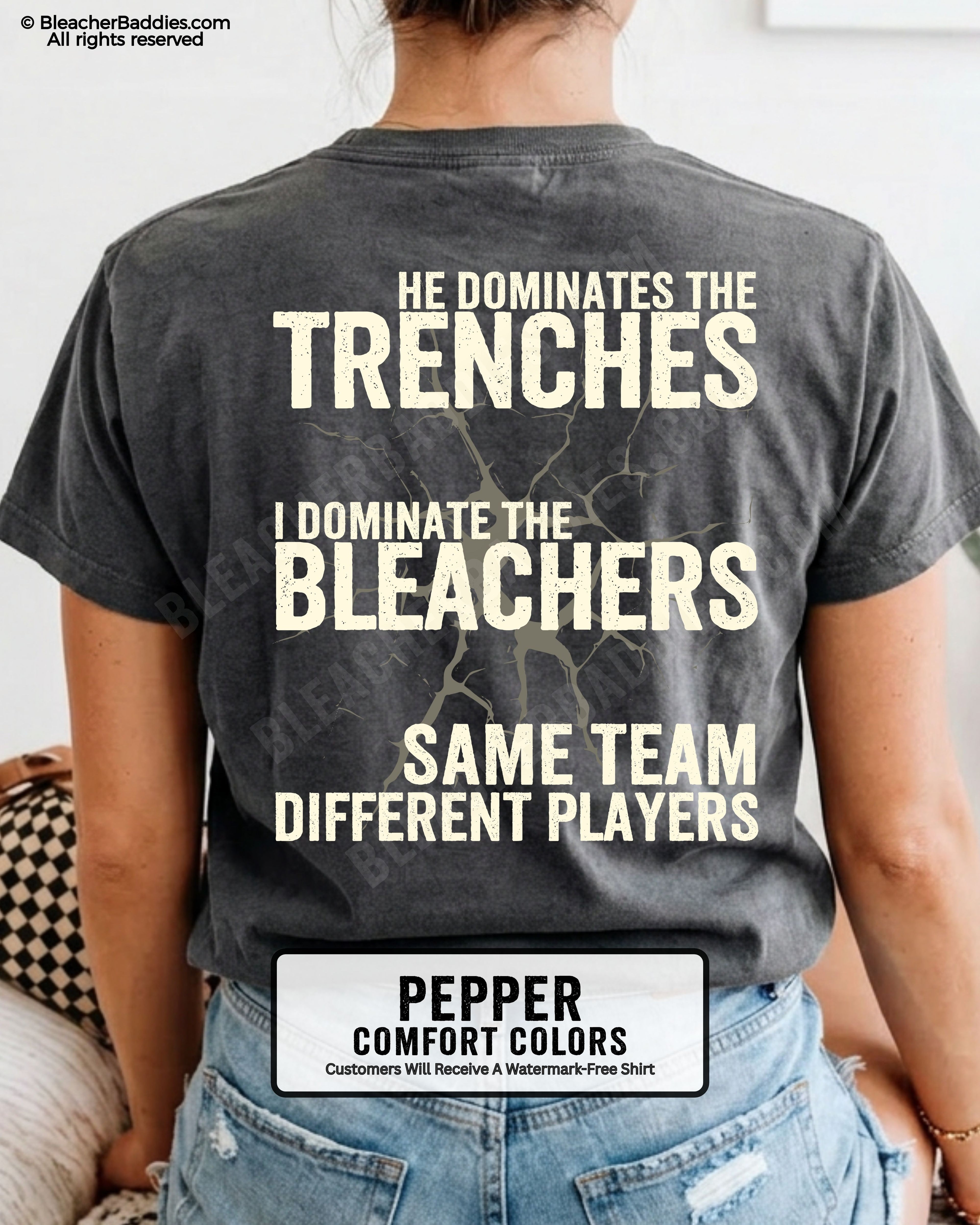 Close-up of woman wearing pepper comfort colors t-shirt back print with distressed text “He Dominates the Trenches I Dominate the Bleachers Same Team Different Players” and cracked design detail