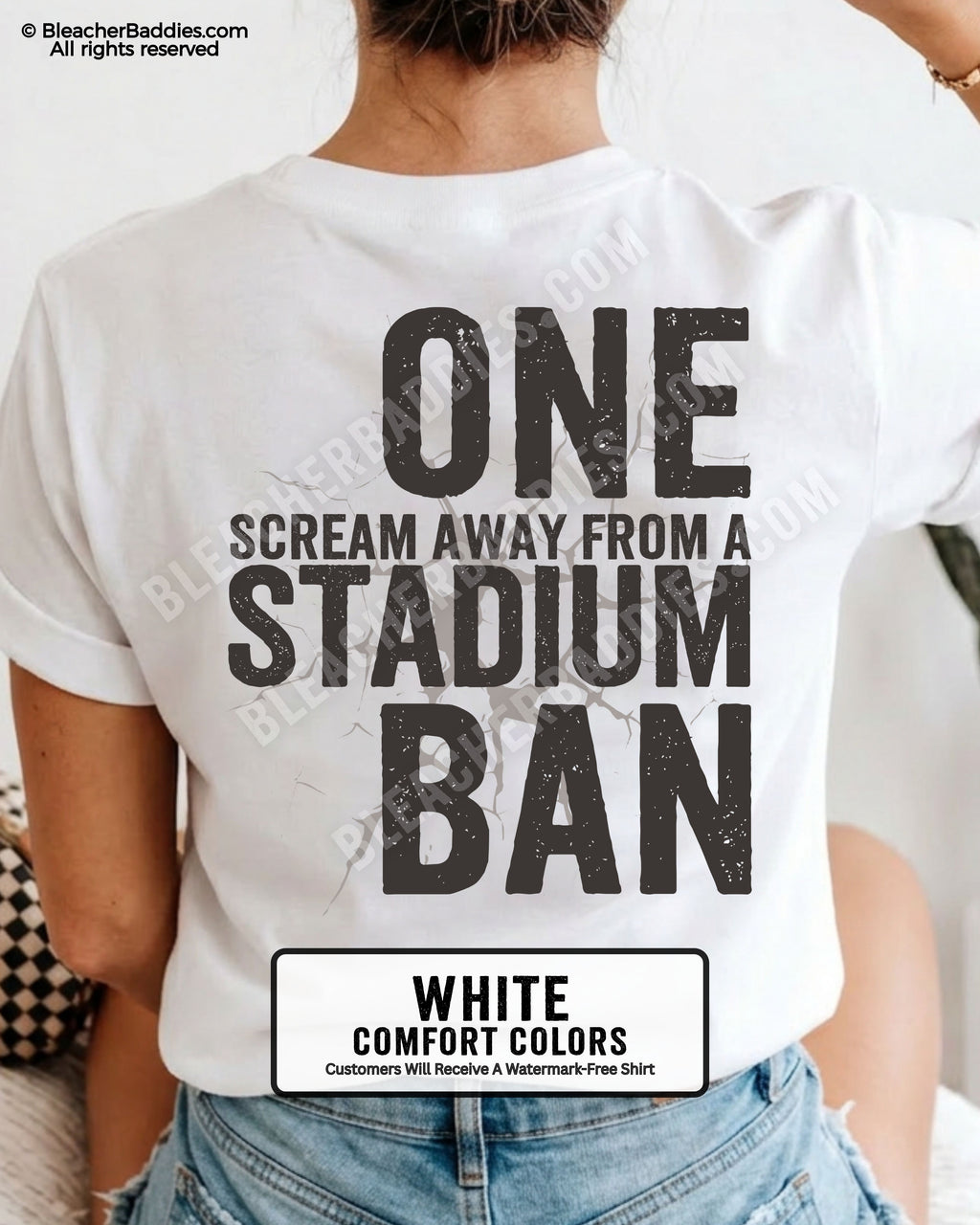 Woman wearing a white t-shirt with a large distressed black back graphic that reads “One Scream Away From a Stadium Ban” with a cracked texture effect across the design.