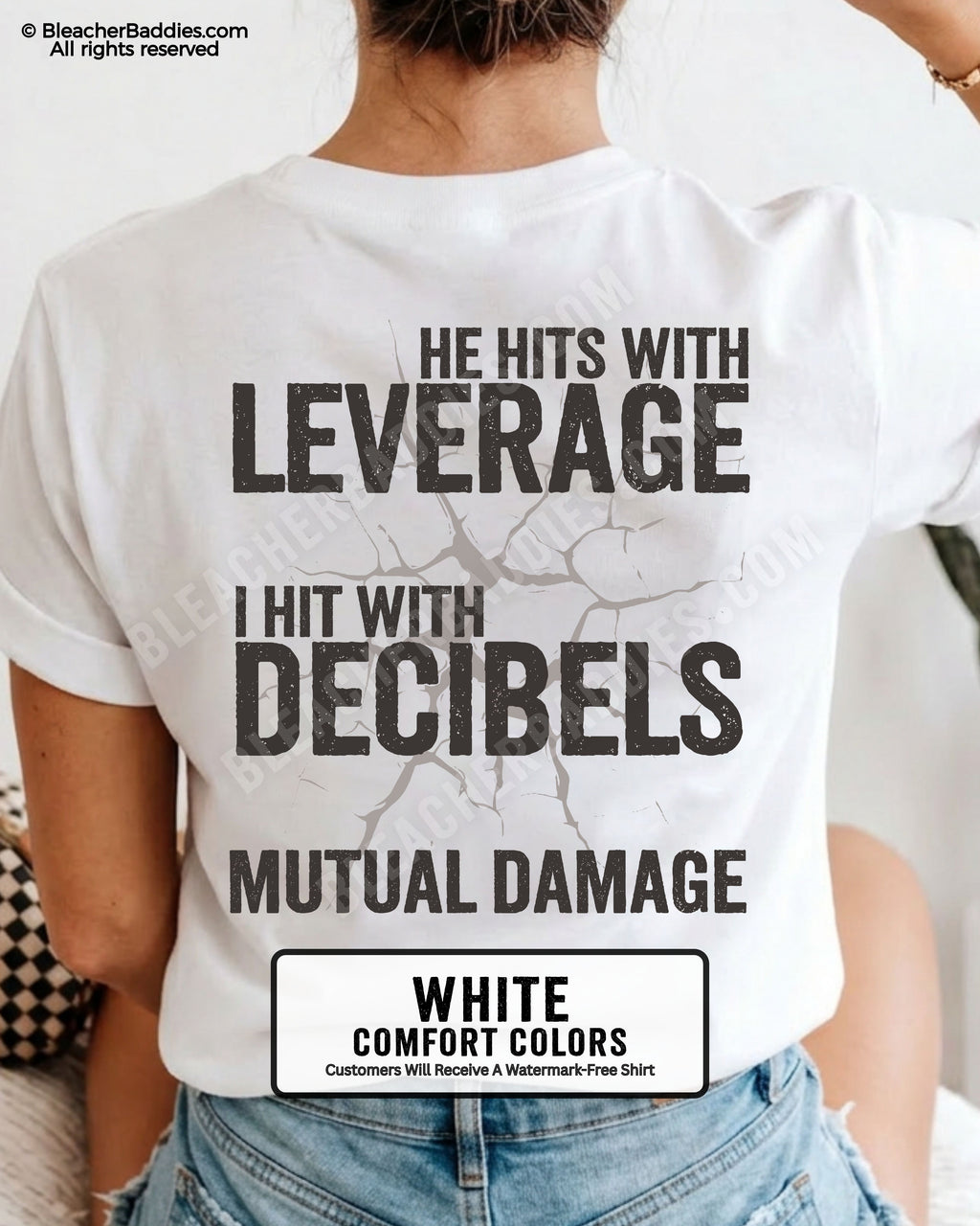 Back view of a white Comfort Colors football mom t-shirt featuring the "He Hits with Leverage, I Hit with Decibels" graphic and "Mutual Damage" printed in a distressed game day design.