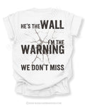 White football mom game day shirt shown from the back featuring a large distressed black graphic that reads “He’s the Wall I’m the Warning We Don’t Miss.”